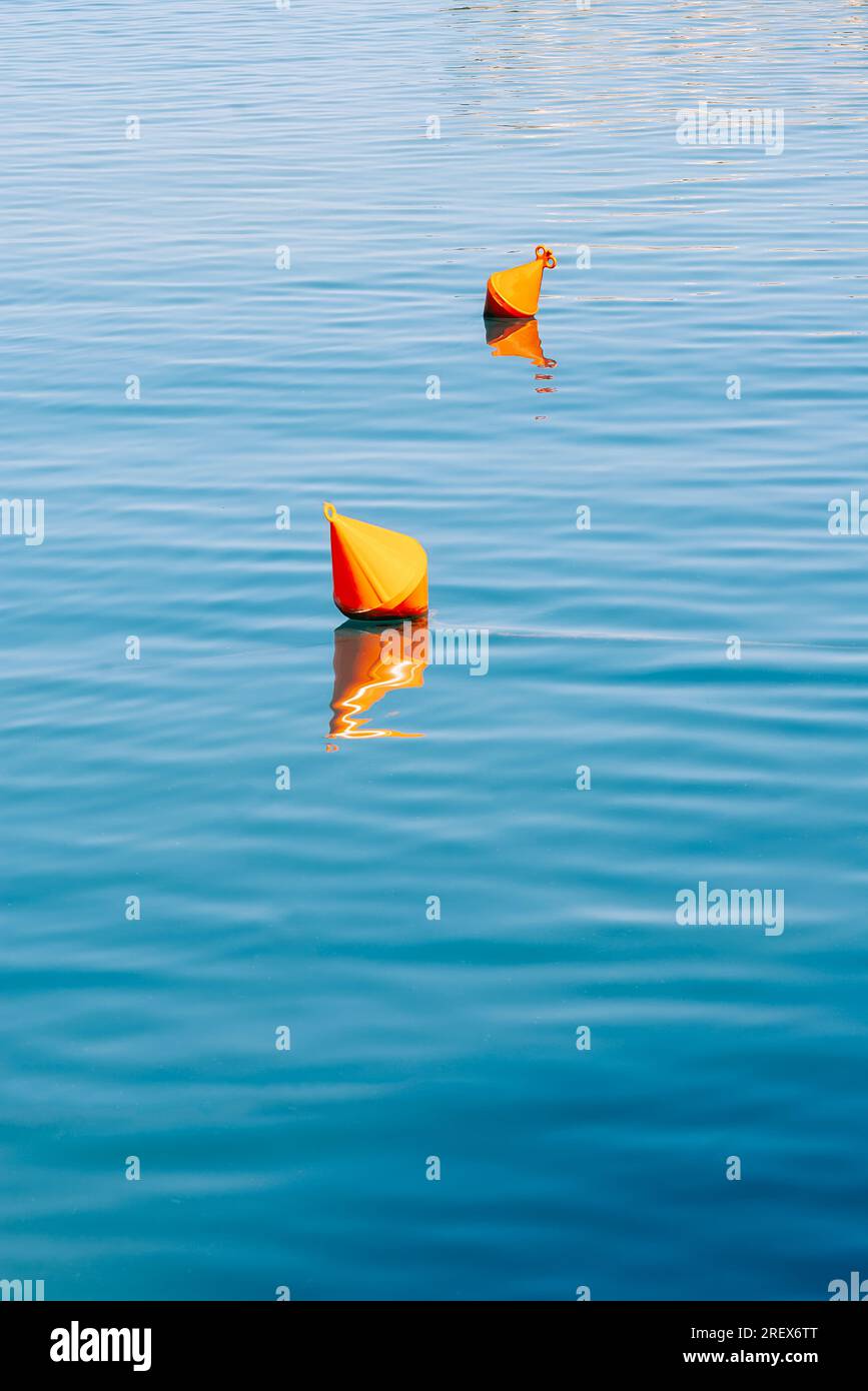 Wasserhintergrund - orangene Bojen auf der Oberfläche des blauen Meerwassers Stockfoto