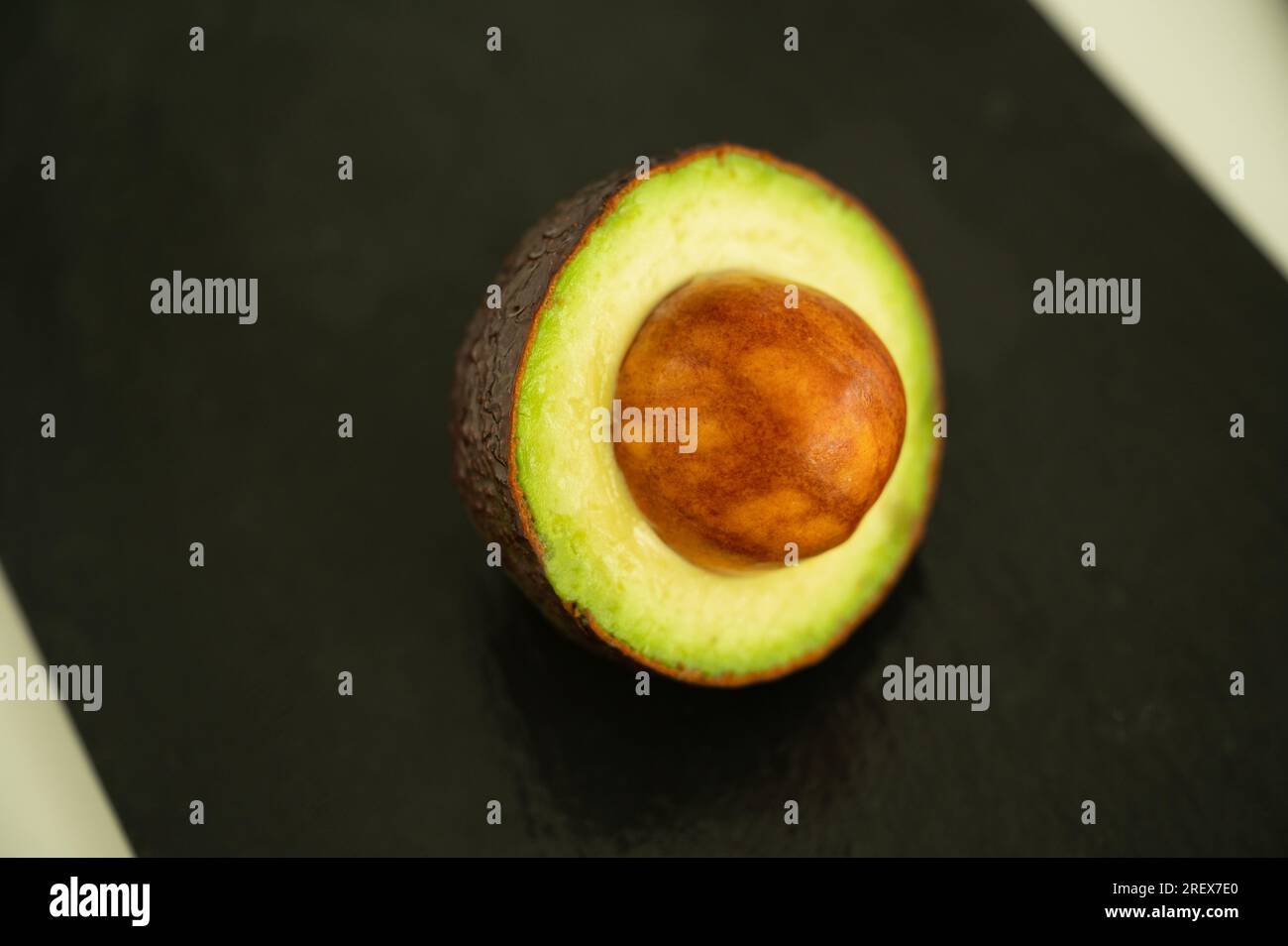 Halber Avocado mit Samen auf schwarzem Hintergrund - gesundes Superfood Stockfoto