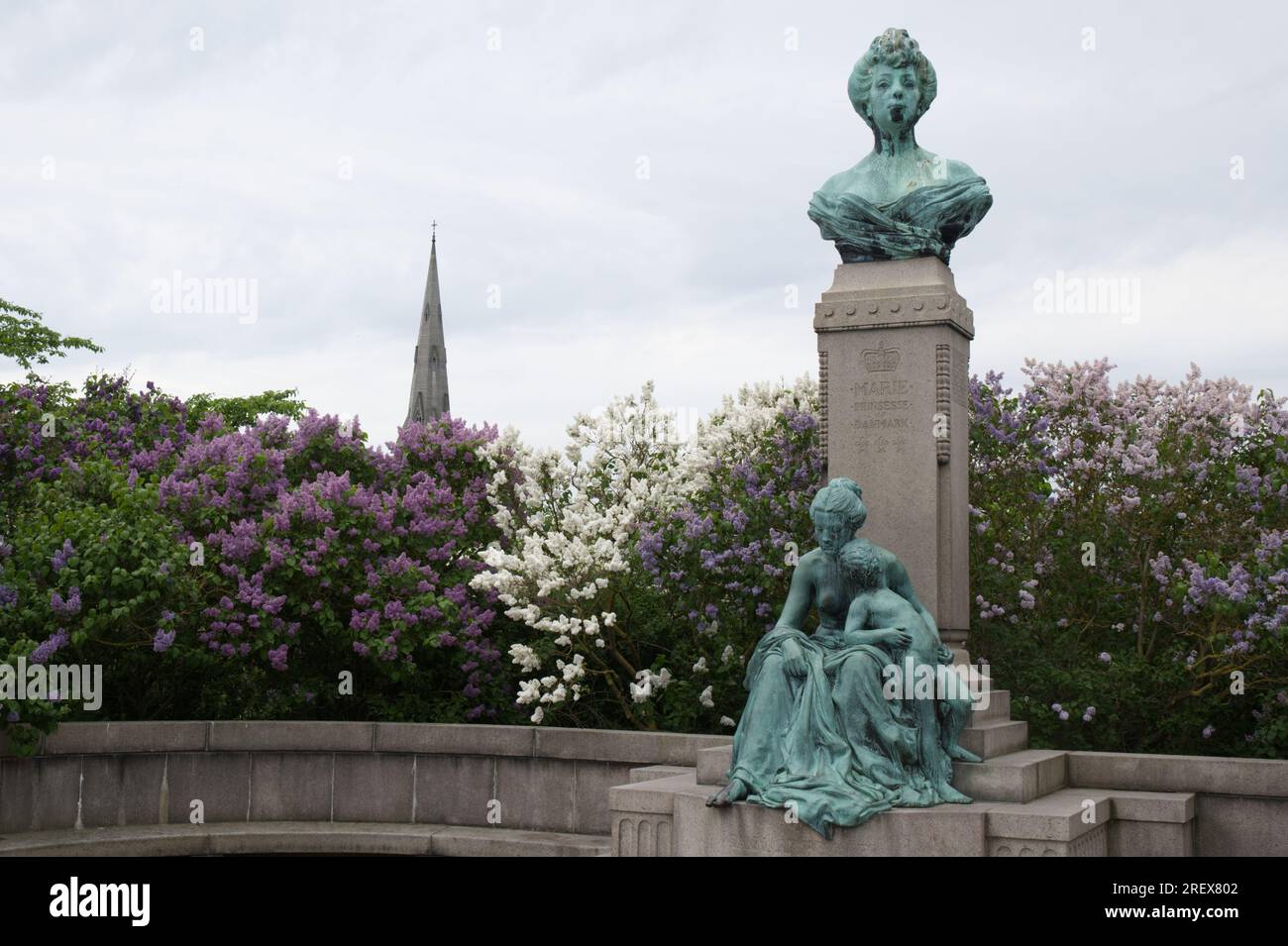Denkmal für Prinzessin Marie von Orleans von Carl Martin-Hansen vor Fliederbäumen mit dem Turm der Kirche St. Alban in Kopenhagen, Dänemark Stockfoto