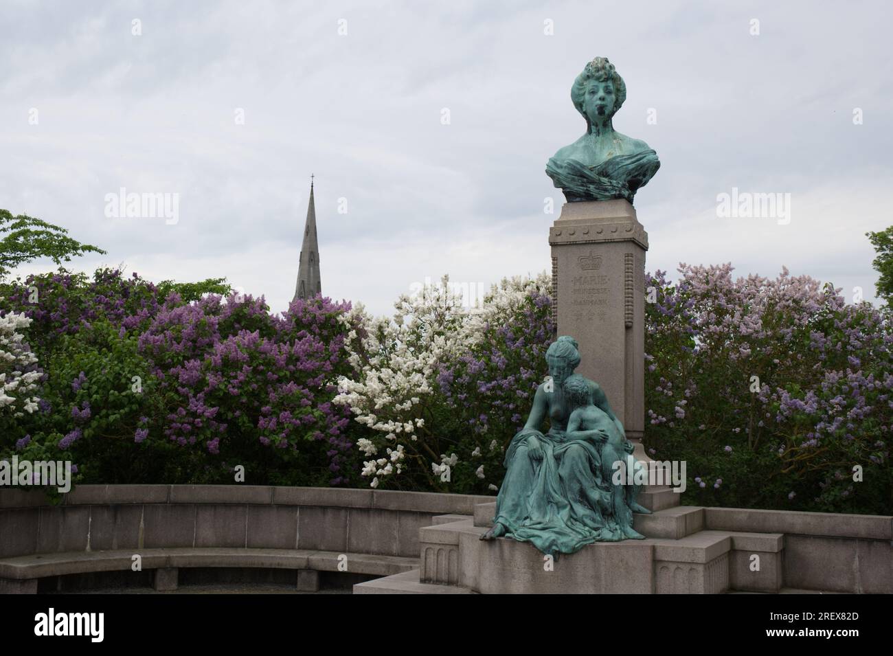 Denkmal für Prinzessin Marie von Orleans von Carl Martin-Hansen vor Fliederbäumen mit dem Turm der Kirche St. Alban in Kopenhagen, Dänemark Stockfoto