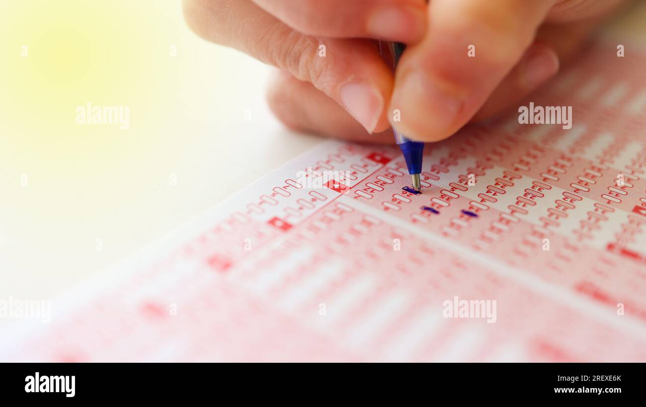 Frau markiert mit Bleistift Zahlen auf dem Lotterieticket. Stockfoto