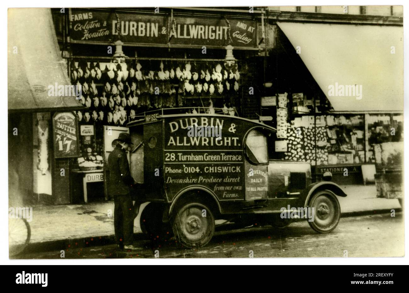 Foto von Durbin & Allwrights Lieferwagen und Fahrer vor dem Laden, der frische Produkte direkt von seinen Devonshire Farmen in Honiton und Colyton verkauft. In diesem Laden werden Hühner, Kaninchen und Butter ausgestellt. Dieser Laden war in Turnham Green Terrace, Chiswick, London, Großbritannien Es gab noch einen Laden in Ealing, London. Ungefähr 1930. Stockfoto
