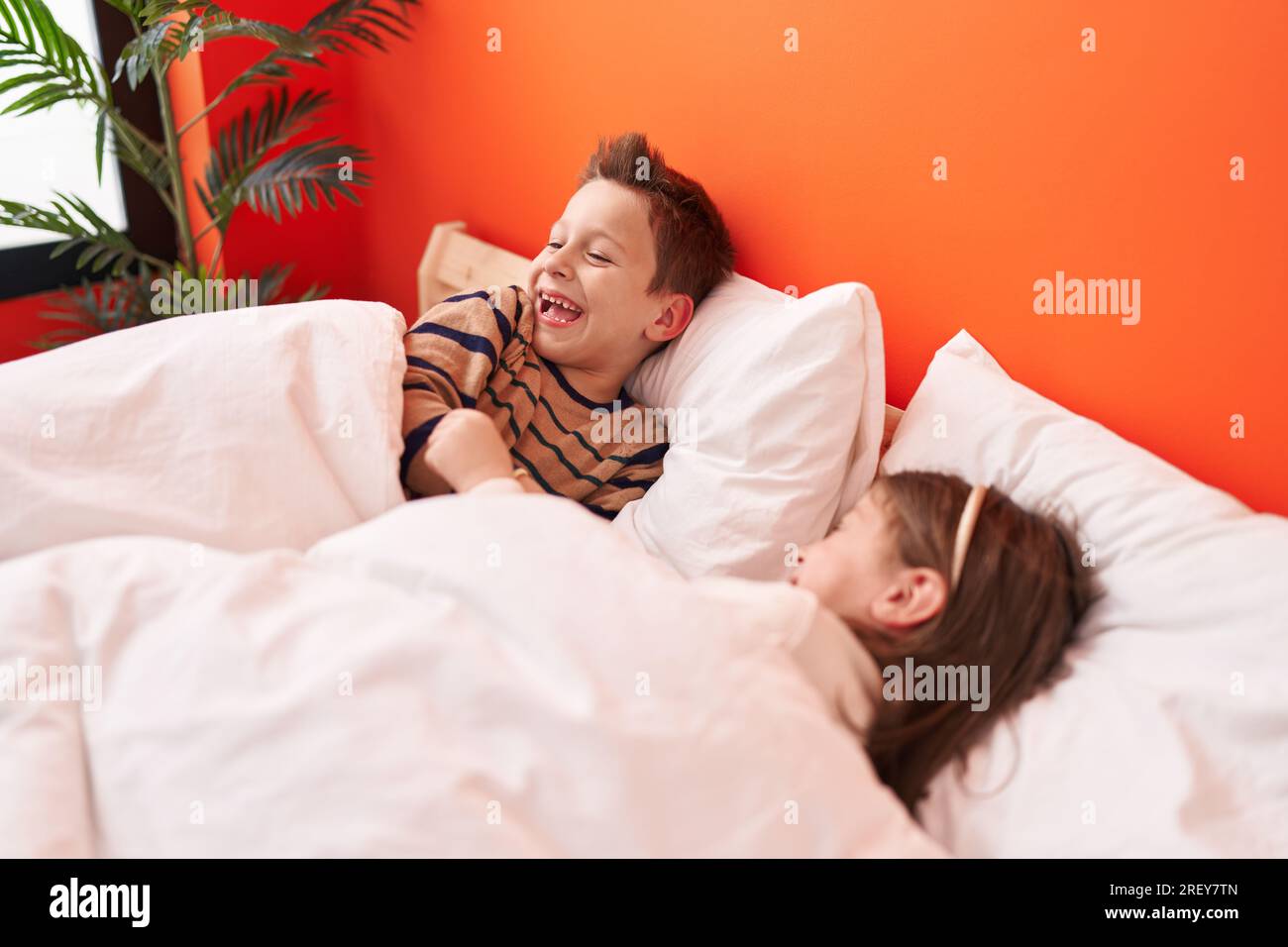 Süßer Junge und Mädchen, die selbstbewusst im Bett im Schlafzimmer lachten Stockfoto