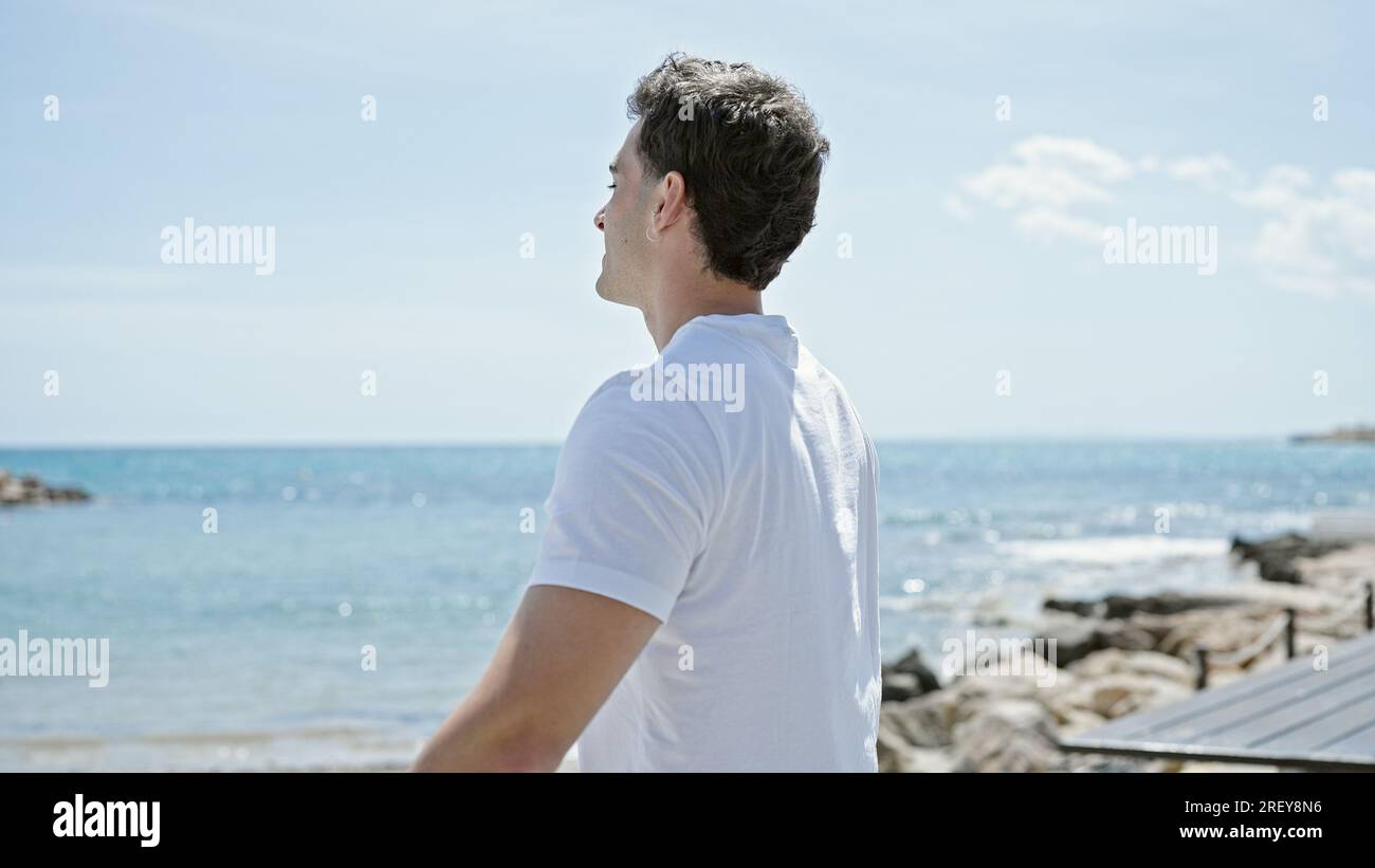 Junger lateinamerikanischer Mann atmet mit offenen Armen am Strand Stockfoto