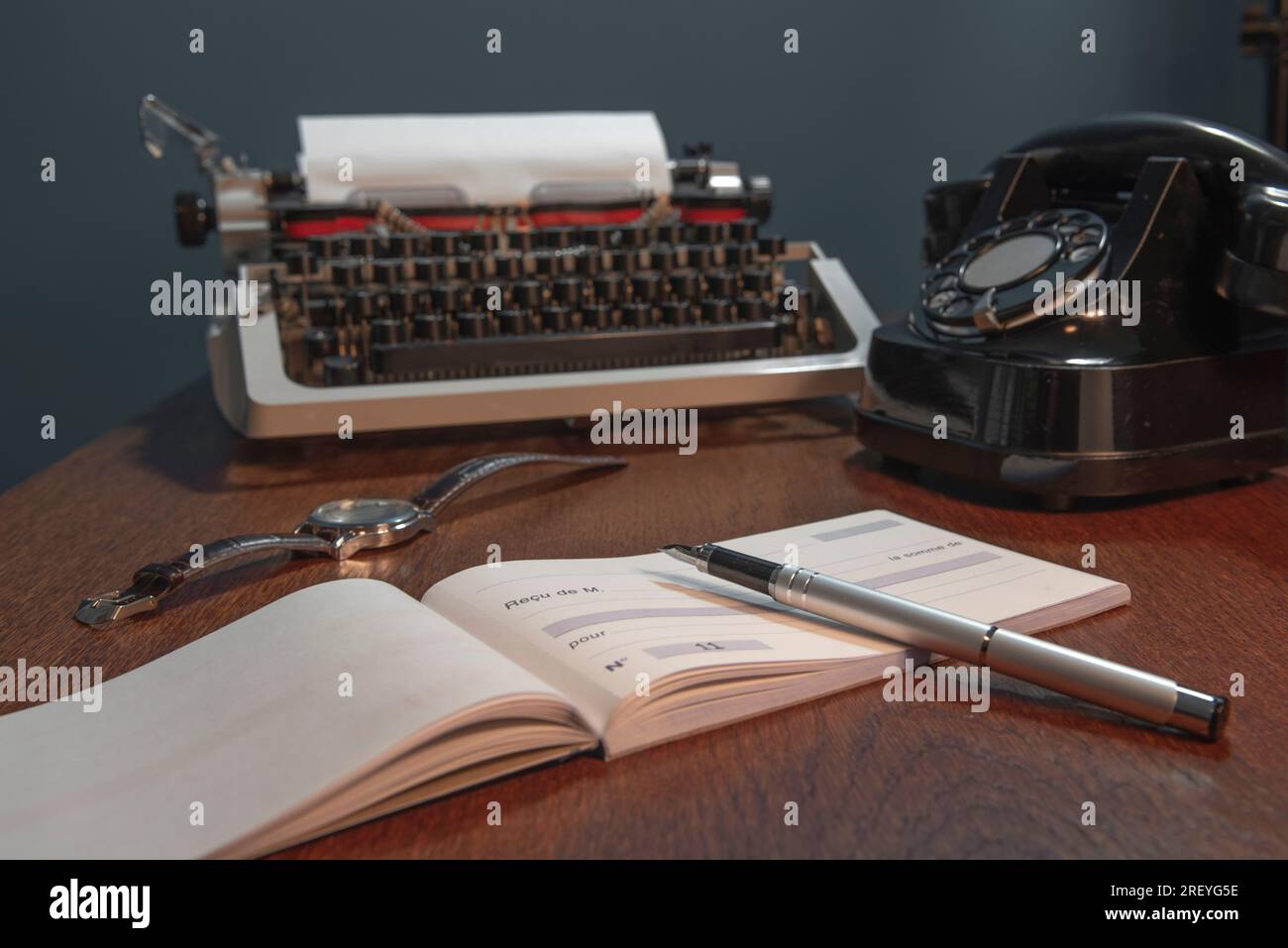 Scheckbuch mit einer leeren Seite für Details auf Französisch. Retro-Konzept mit altem Telefon, Tintenstift und Schreibmaschine. In Farbe Stockfoto