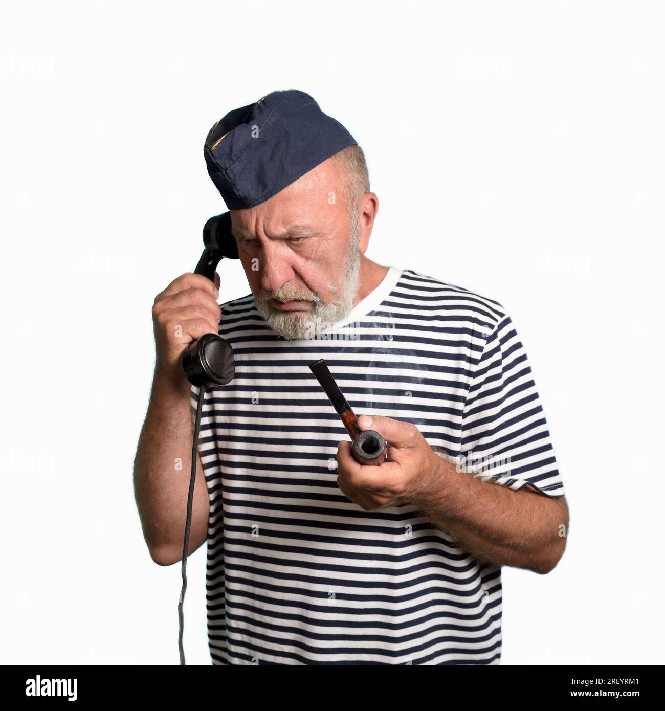 Ein alter Seemann mit einer Rauchpfeife. Empfängt einen Befehl über das Telefon. Weißer Hintergrund. Porträt Stockfoto