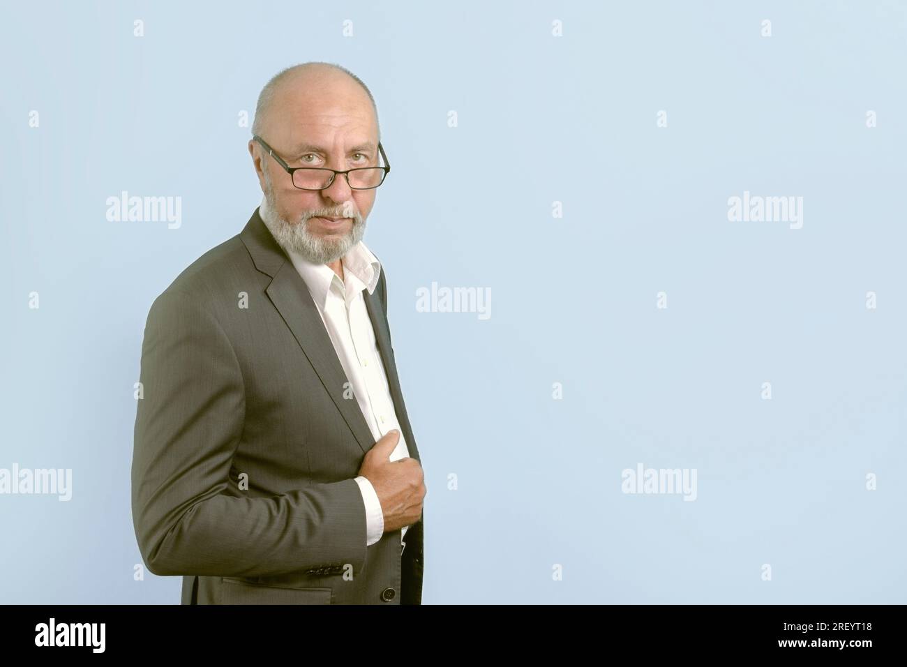 Porträt eines älteren Mannes im klassischen Anzug, Brille, grauer Bart. Auf hellblauem Hintergrund. Speicherplatz kopieren. Banner Stockfoto