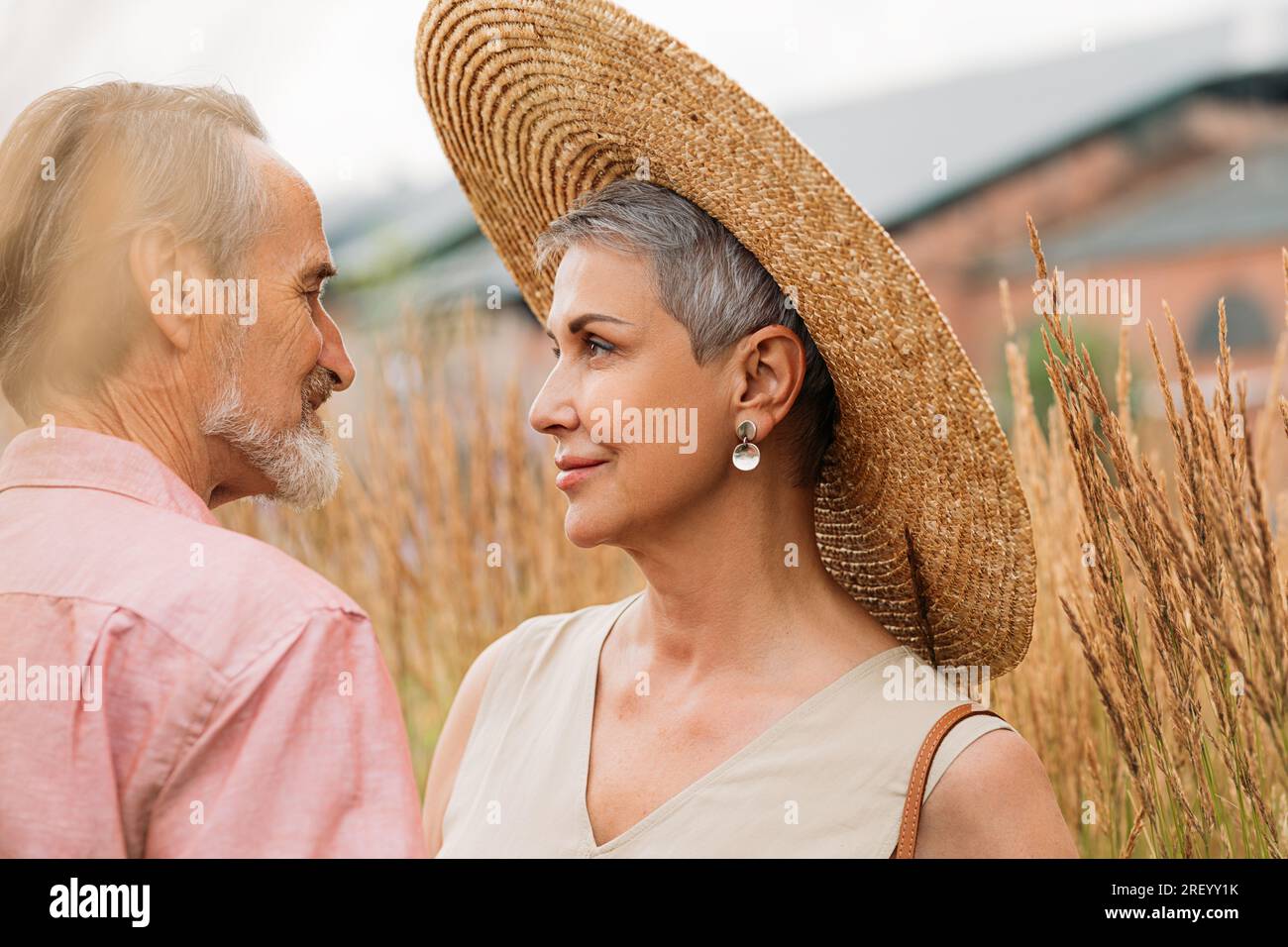 Alte Frau mit kurzen grauen Haaren, die einen Strohhut trägt und ihren Mann ansieht Stockfoto