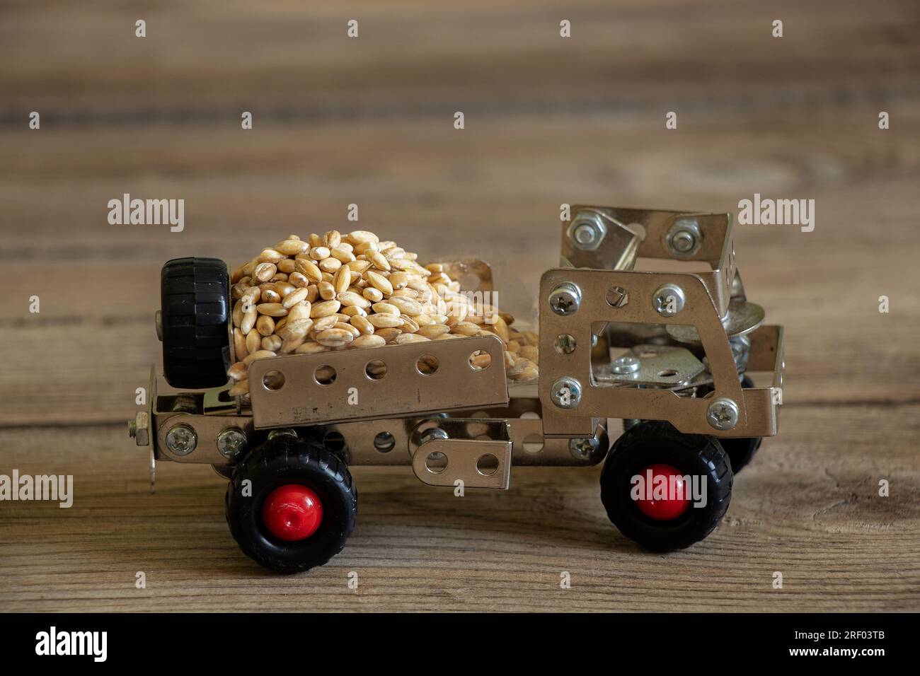 Frachttransport von Getreide auf einem Schreibmaschinenwagen für Kinder, hergestellt aus einem Metallkonstruktor auf einer Holzplatte, Logistik, Transport von Getreide Stockfoto