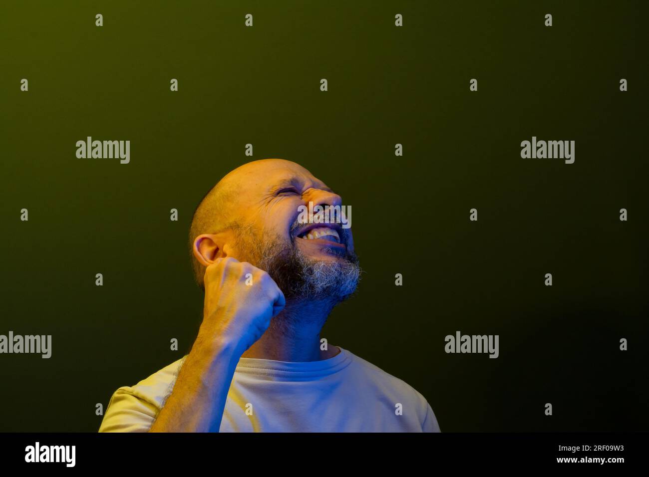 Ein glücklicher, zufriedener Mann, der Kraft und Leistungsgesten zeigt. Erfolgskonzept. Isoliert auf dunkelgrünem Hintergrund. Stockfoto