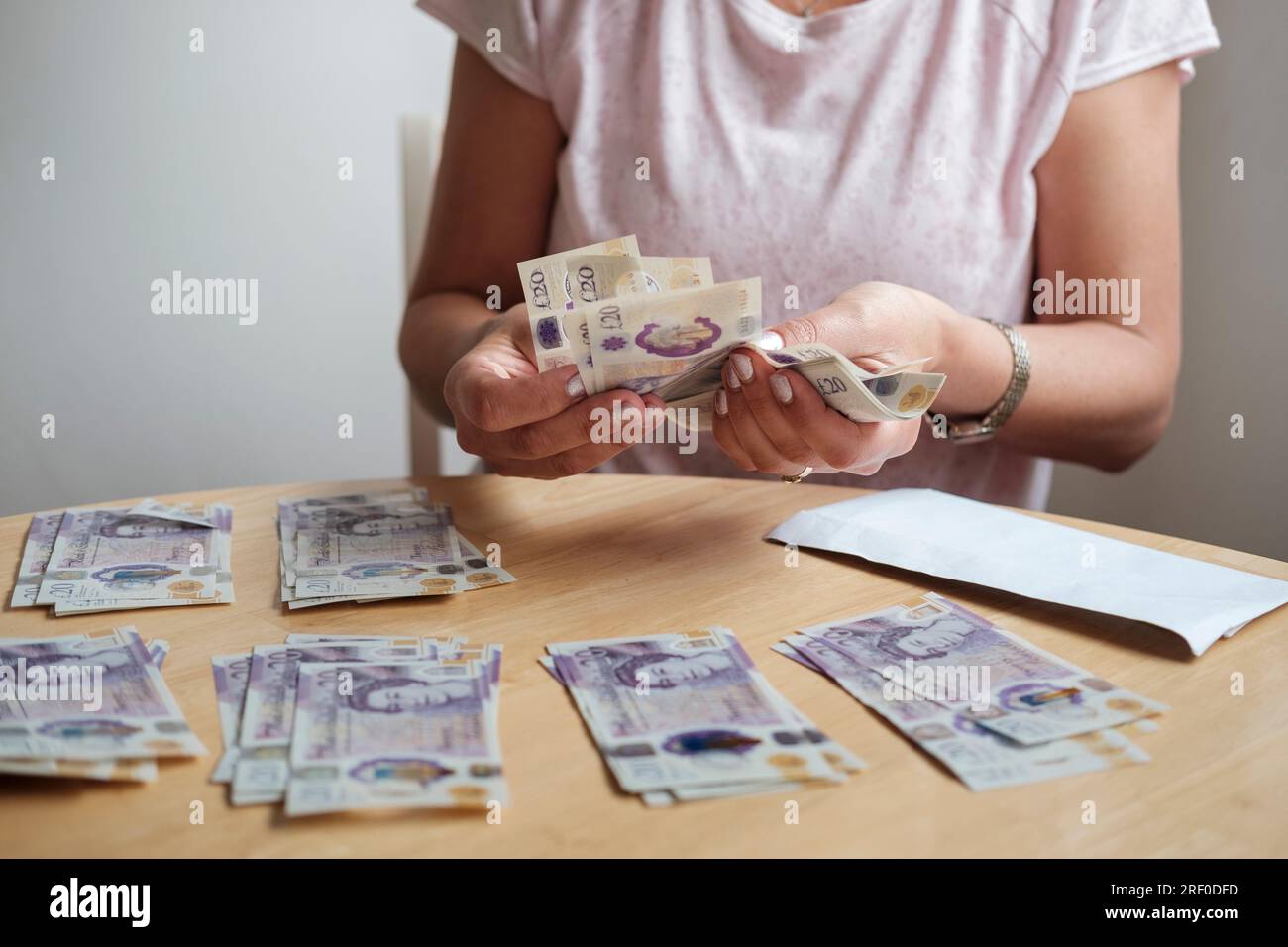 Lebenshaltungskosten, UK-Frau zählt Bargeld, Pfund Sterling, Ersparnisse, Rechnungen bezahlen. Stockfoto