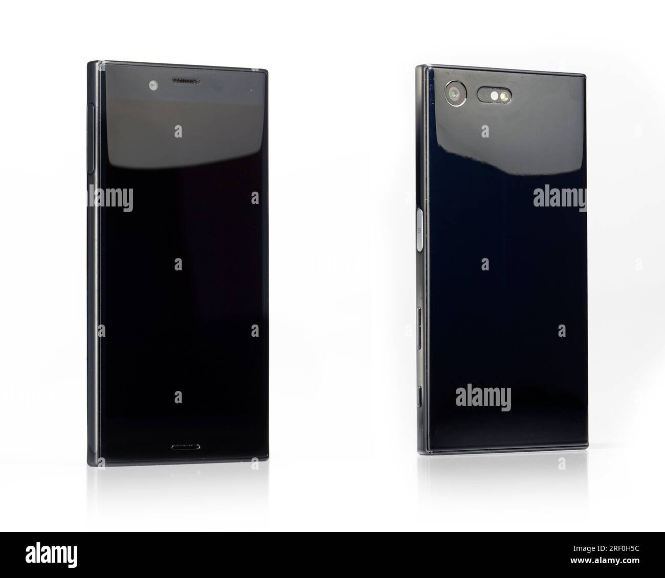 Flaches schwarzes Gebrauchttelefon – Smartphone von hinten und vorne, auf weißem Hintergrund. Mit starken Gebrauchsspuren und einer Reflexion im Boden. Stockfoto