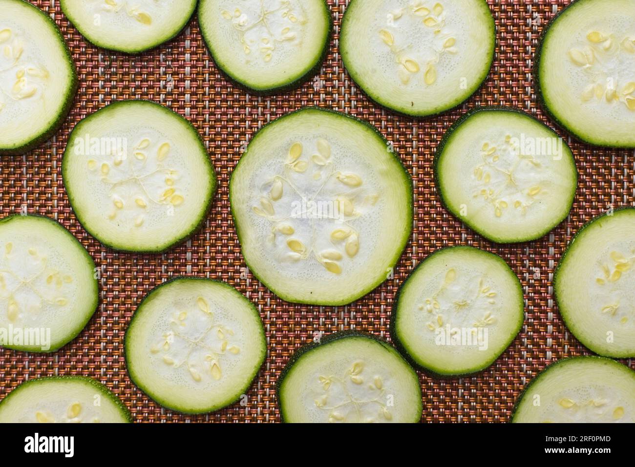Ein flach liegendes Foto von kleinen Zucchinischeiben, die auf einer Matte liegen, die in der Sonne trocknet. Stockfoto