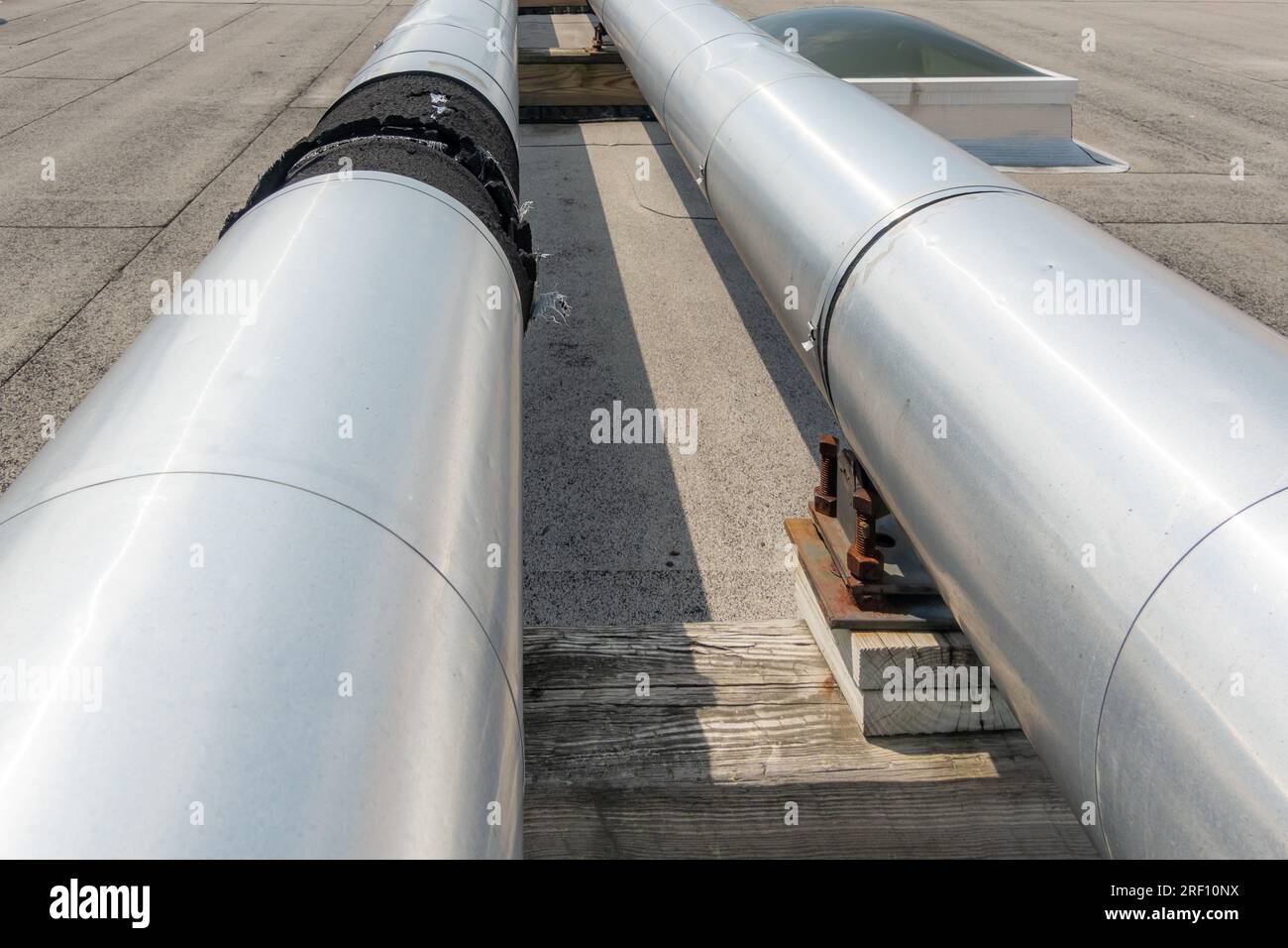 Dachmontierte industrielle isolierte HLK-Rohre auf grauem Dach und Holzstützen. Stockfoto