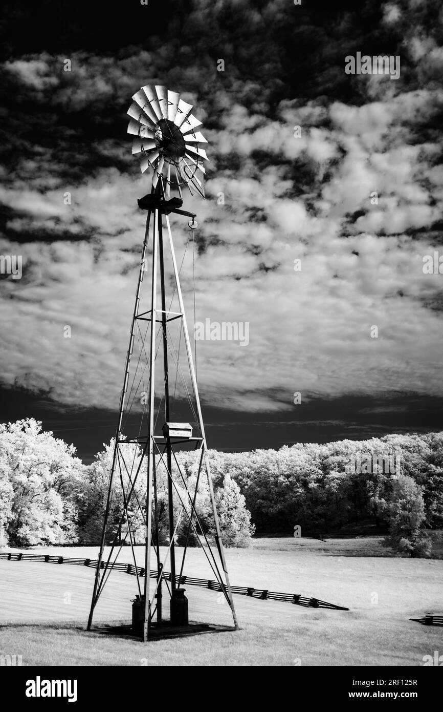 Ein kontrastreiches Infrarotbild einer alten Windmühle bei Seymour, IN. Der Himmel ist tiefschwarz. Im Hintergrund wird ein geteilter Schienenanschlag angezeigt. Stockfoto