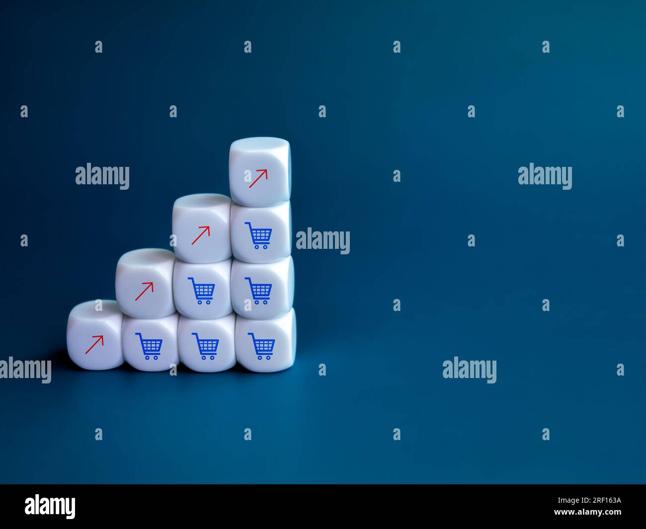 Roter Aufwärtspfeil und blaue Einkaufswagen-Symbole auf weißem Würfelblock als Wachstumsdiagramm auf blauem Hintergrund mit Platz zum Kopieren. Online-sh Stockfoto