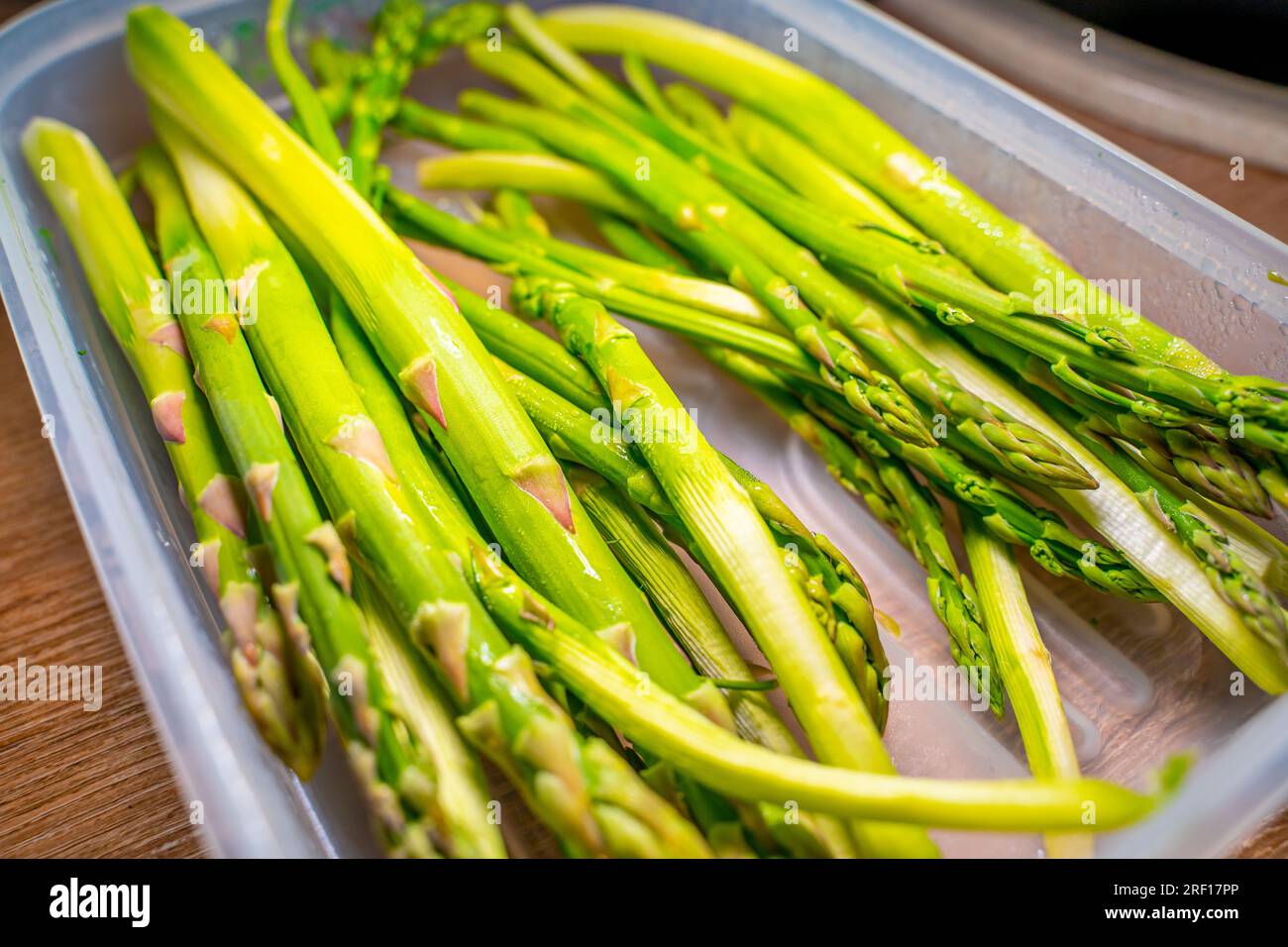 Grüner Spargel schießt in Nahaufnahme eines Lebensmittelbehälters Stockfoto