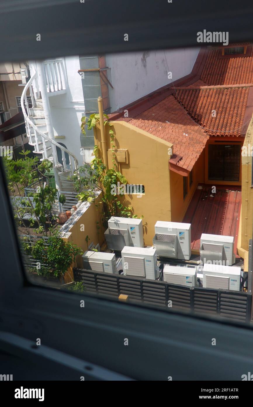 Rückfenster mit Blick auf Klimaanlagen, Terrassen, geflieste Dächer und traditionelle Feuertreppe in den Hinterhöfen von Little India, Singapur. KEIN MR ODER PR Stockfoto