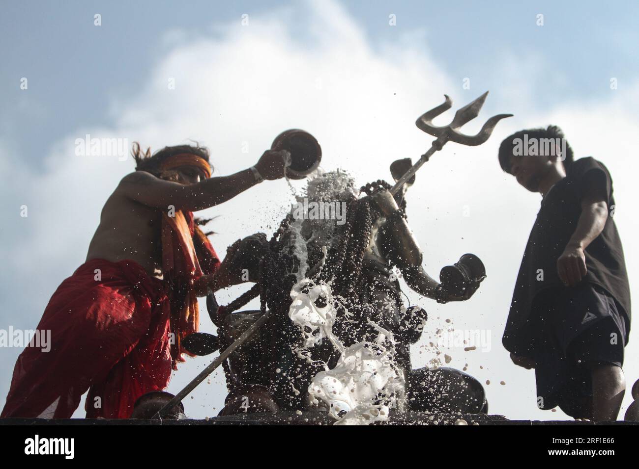 Ein hinduistischer Priester gießt Milch ein, während er Idol von Lord Shiva am Montag, den 31. Juli 2023, im Shiva-Tempel in Kathmandu, Nepal, betet. Der heilige Monat o Stockfoto