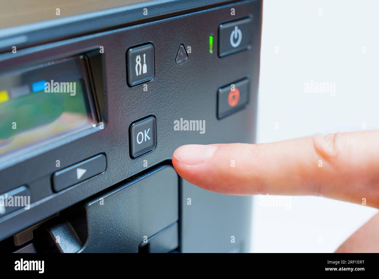 Drücken Sie selbstbewusst die Taste „OK“ auf einem Drucker in einer Nahaufnahme. Stockfoto