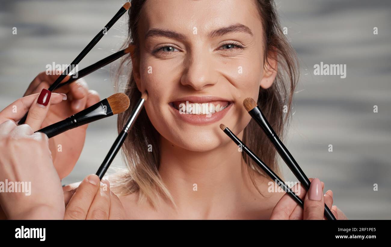 Team von Maskenbildnern, die das Schönheitsmodell überarbeiten, Spezialisten, die Pinsel und Werkzeuge verwenden, um einen strahlenden Look zu schaffen. Junge, makellose Frau, die nährend und sanft behandelt wird. Schließen. Stockfoto
