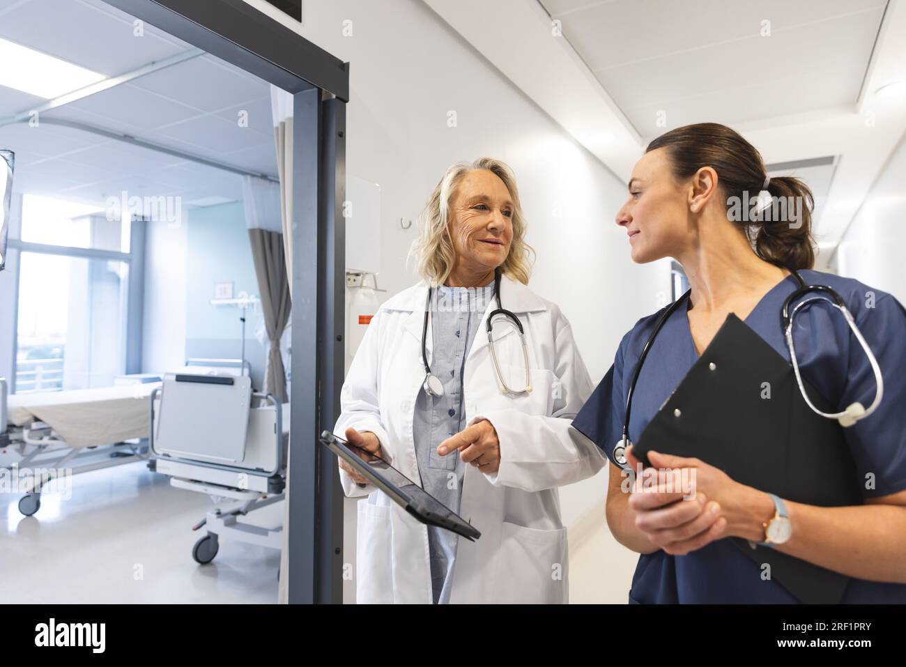 Glückliche weisse Ärztinnen mit Stethoskopen, die Tabletten im Krankenhaus benutzen Stockfoto