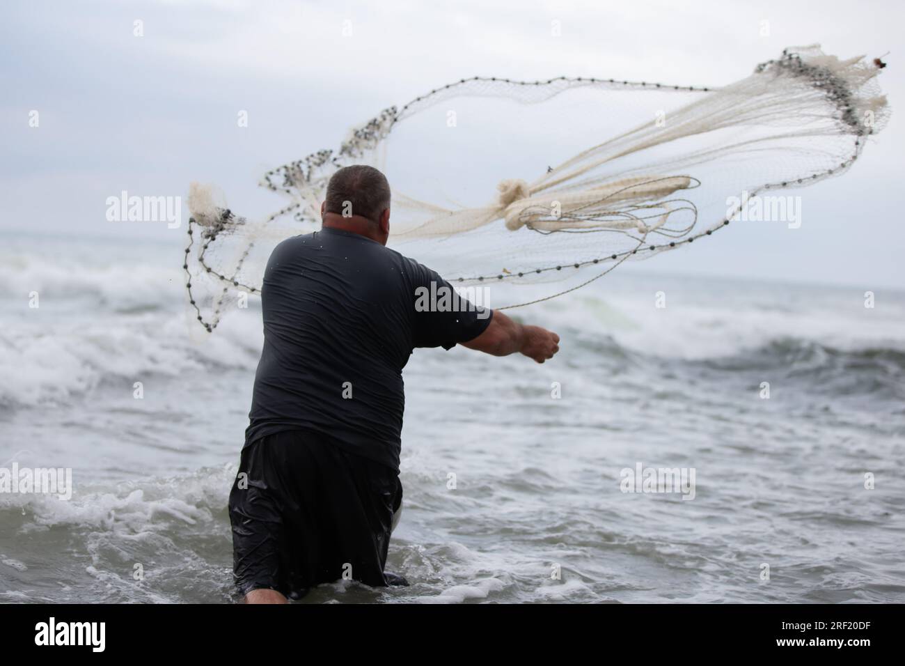 Ein Fischer wirft ein Fischernetz ins Meer Stockfotografie - Alamy