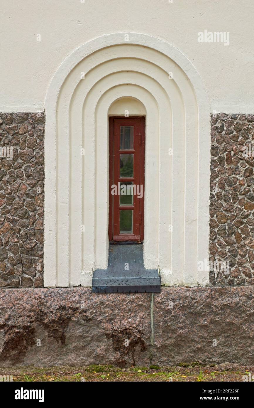 Rotes gerahmtes Fenster mit dekorativem Bogen an alten Steinwänden. Stockfoto