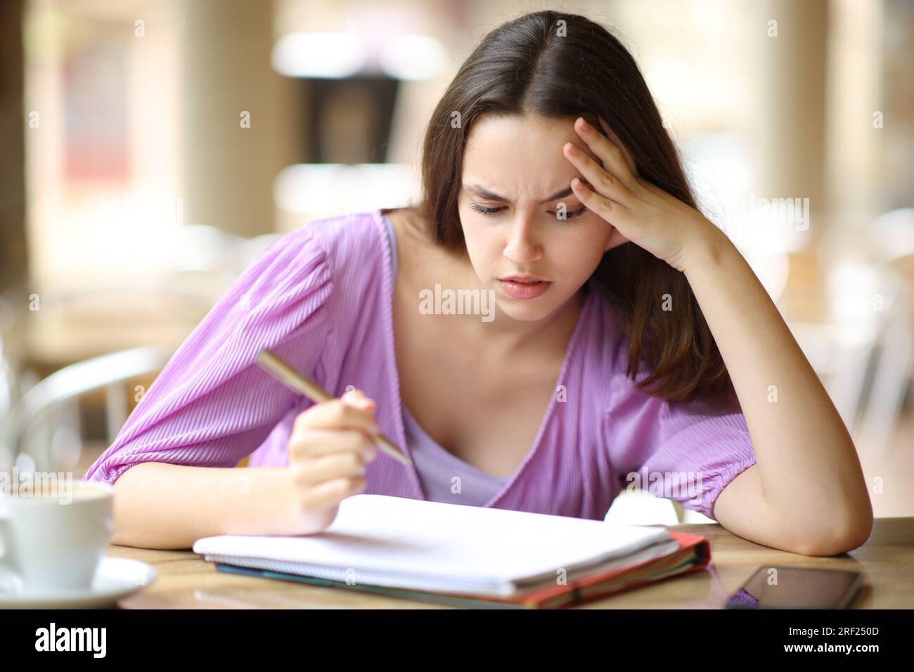 Gestresster Student, der sich Notizen auf einer Barterrasse auswendig lernt Stockfoto