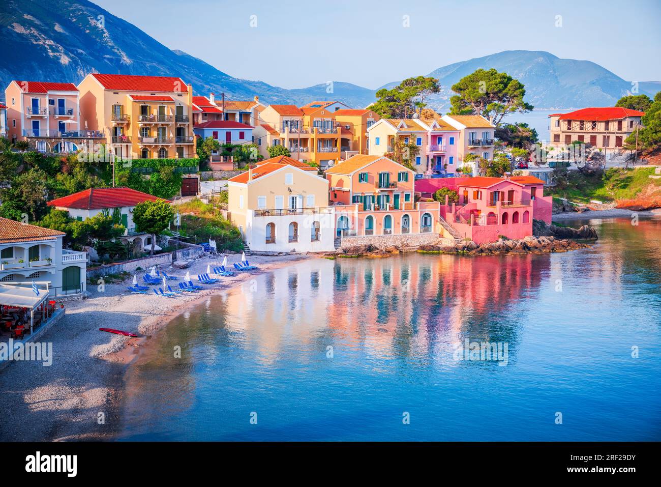 Assos, Griechenland. Sonnenaufgang in Kefalonia, malerisches Dorf eingebettet auf den idyllischen Ionischen Inseln. Wunderschöne farbenfrohe Häuser und türkisfarbene Bucht. Stockfoto