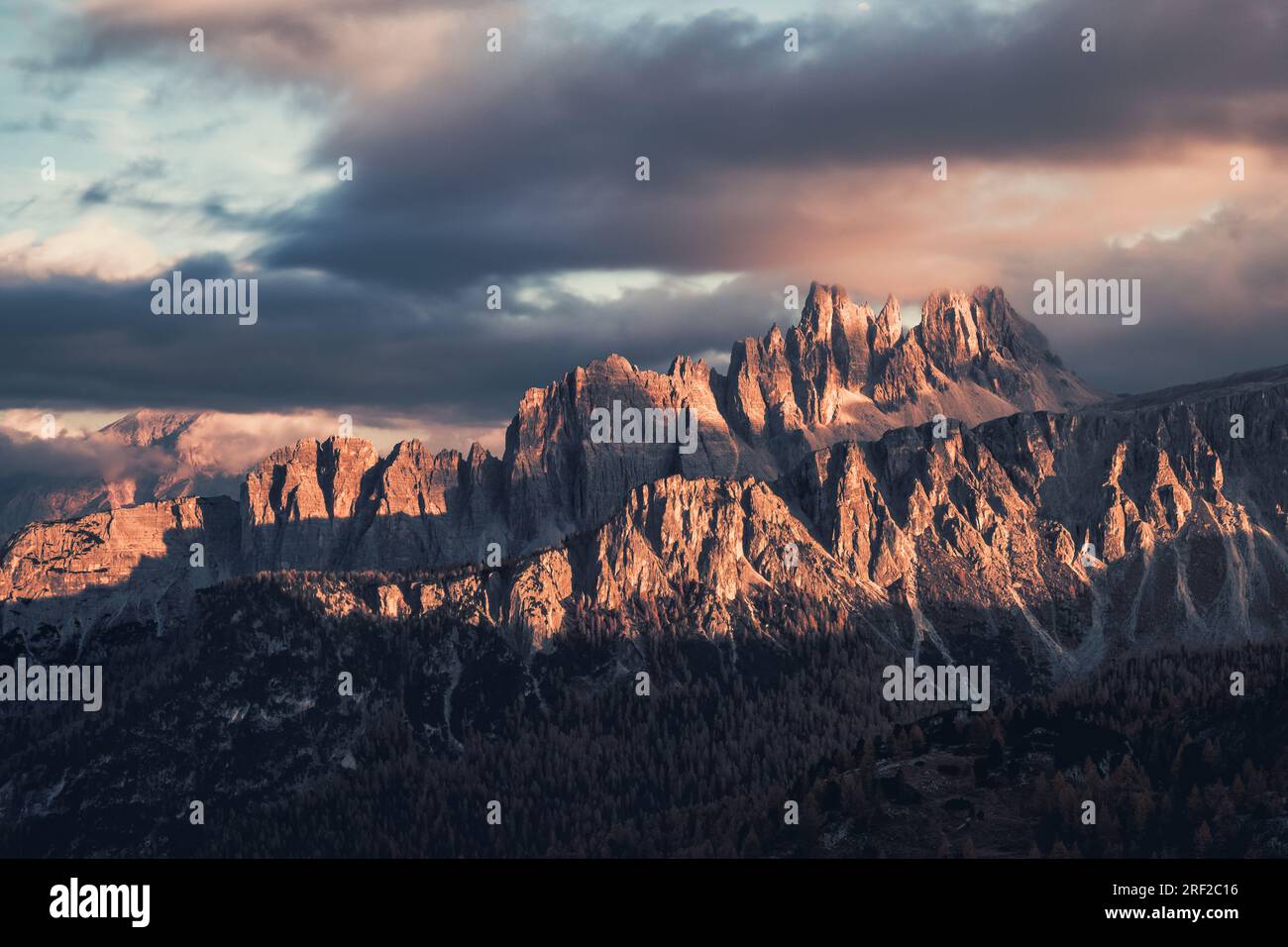 Panoramablick auf hohe felsige Berge bei bewölktem Sonnenuntergang Stockfoto