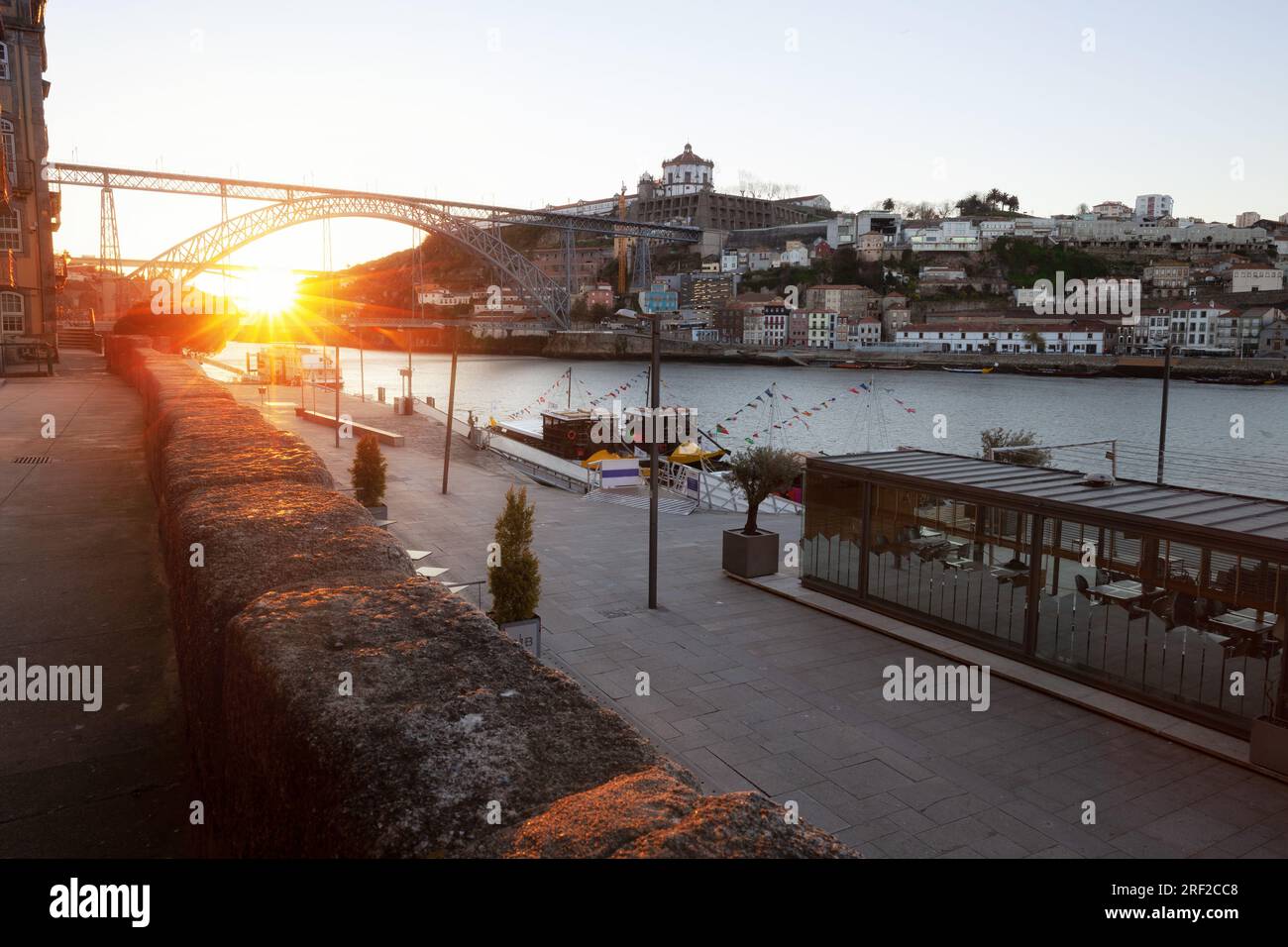 Blick auf die Altstadt von Ribeira in Porto, Portugal, mit malerischen Häusern am Flussufer, beleuchtet von frühmorgendlichem Sonnenlicht und Booten, die auf Touristen warten Stockfoto