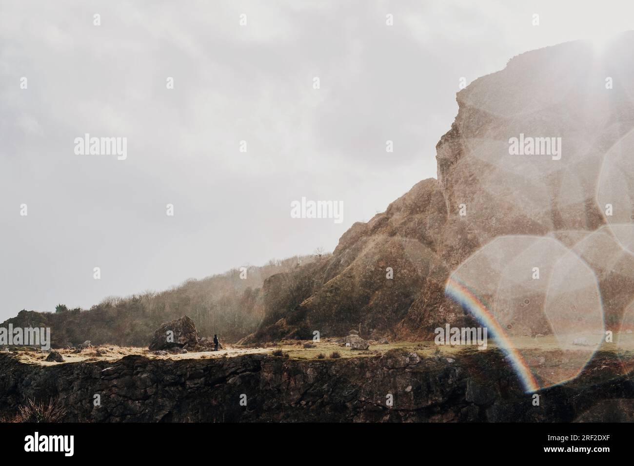 Eine kleine Figur stand in hinterleuchtetem Regen an der zerklüfteten walisischen Küste Stockfoto Eine kleine Figur stand in hinterleuchtetem Regen an der zerklüfteten walisischen Küste Stockfoto