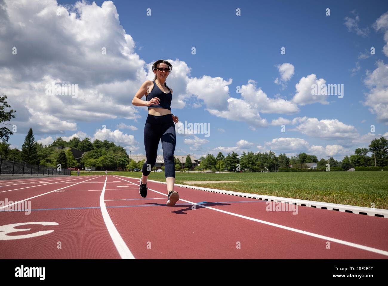 Eine gesunde junge Frau lächelt und joggt und läuft auf einer Rennstrecke Stockfoto