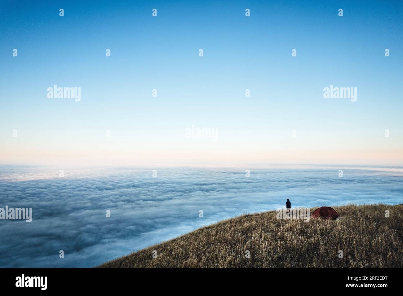 Ein Mann blickt über Nebel, während er campen geht, Big Sur, Kalifornien Stockfoto