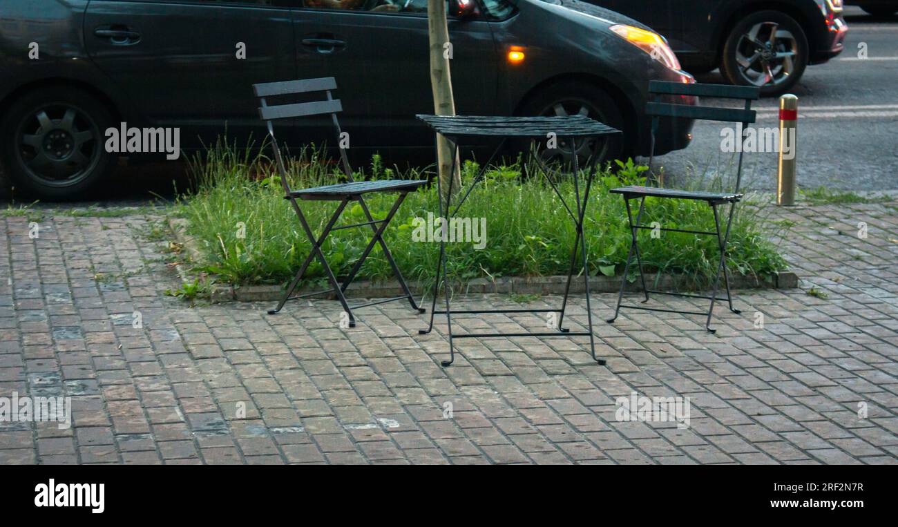 Tisch und Stühle im Straßencafé. Straßencafé an regnerischen Tagen. Kleines lokales Unternehmen. Leeres Café im Herbst. Öffentliche Bereiche zum Essen im Freien. Stockfoto