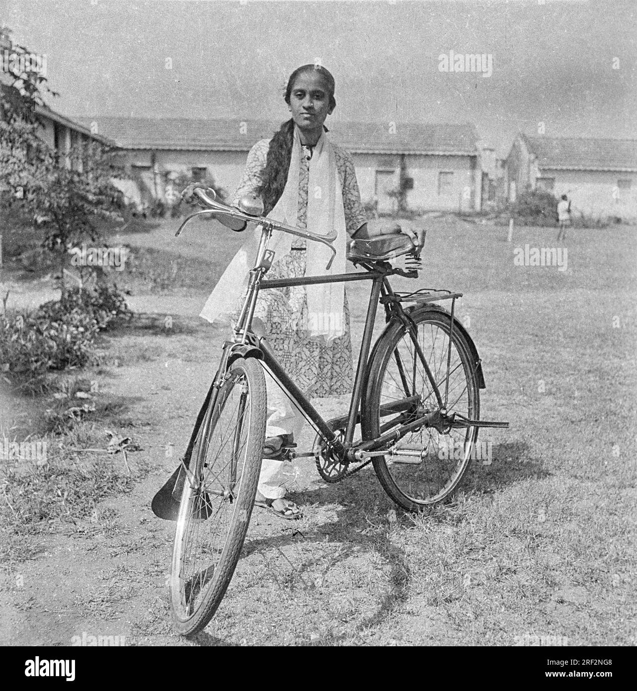 Altes, klassisches 1900er-schwarzweißes Bild einer indischen Frau, die ein Fahrrad mit Salwar Kameez India 1940er trägt Stockfoto