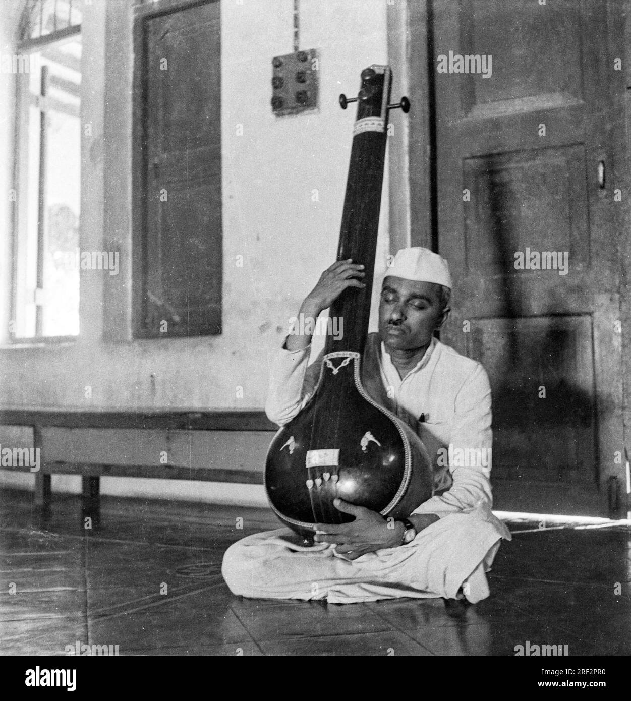 Altes, 1900er Jahre altes Schwarz-Weiß-Bild eines indischen Mannes, der das Instrument Tampura India 1940er spielt Stockfoto