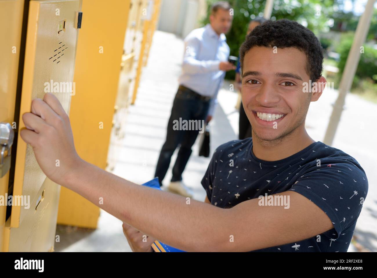 Ein junger, gutaussehender Mann öffnet die Schließfachtür aus Metall Stockfoto
