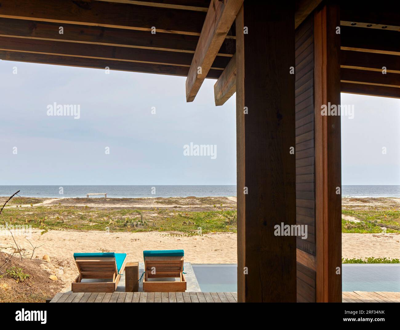 Überdachte Holzterrasse mit Blick vom Pool zum Meer. Punta Pajaros, Oaxaca, Mexiko. Architekt: Alberto Kalach, 2019. Stockfoto