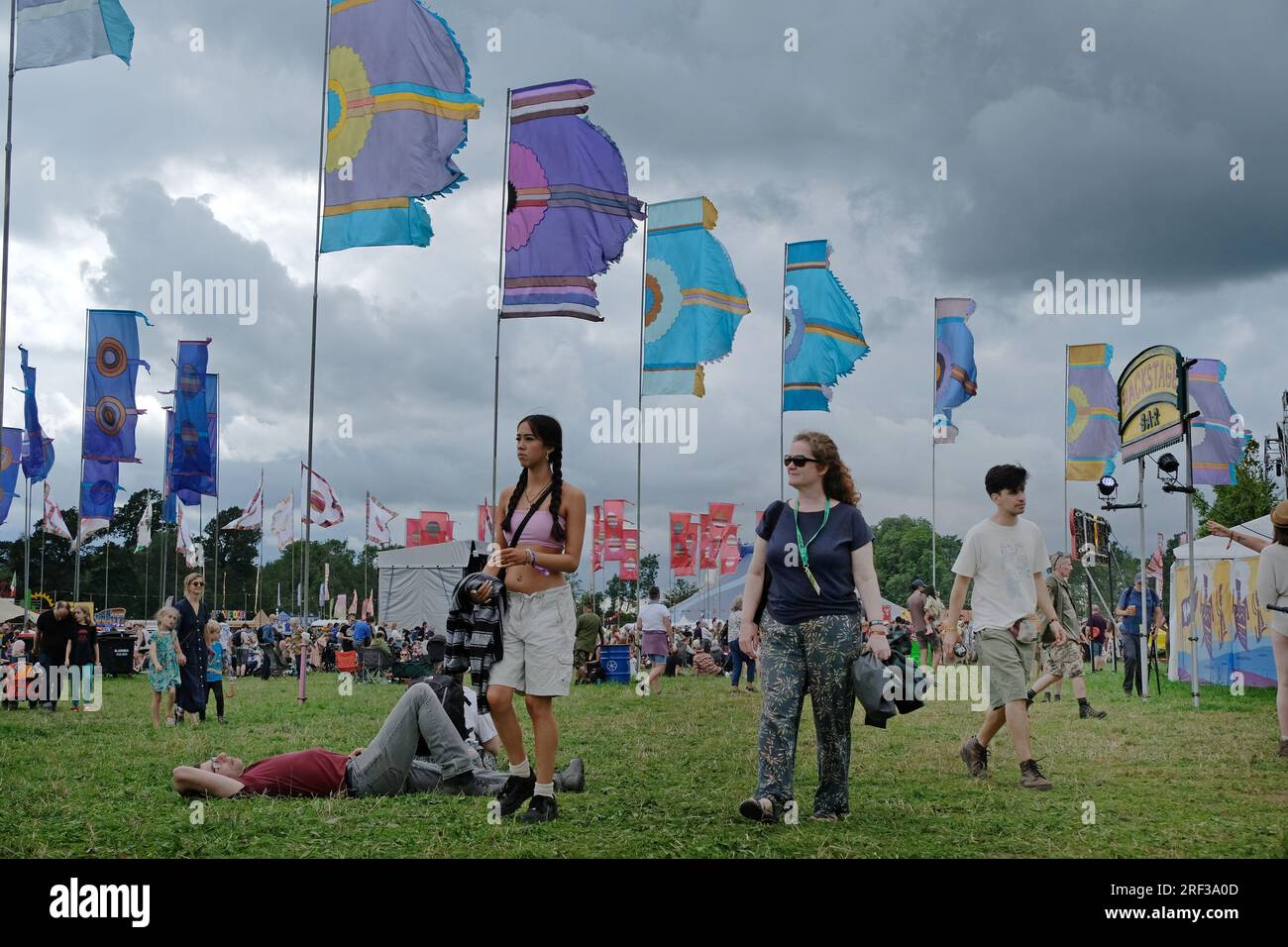 Festivalbesucher vor den womad-Flaggen an einem windigen, bedeckten und bewölkten Tag. Stockfoto