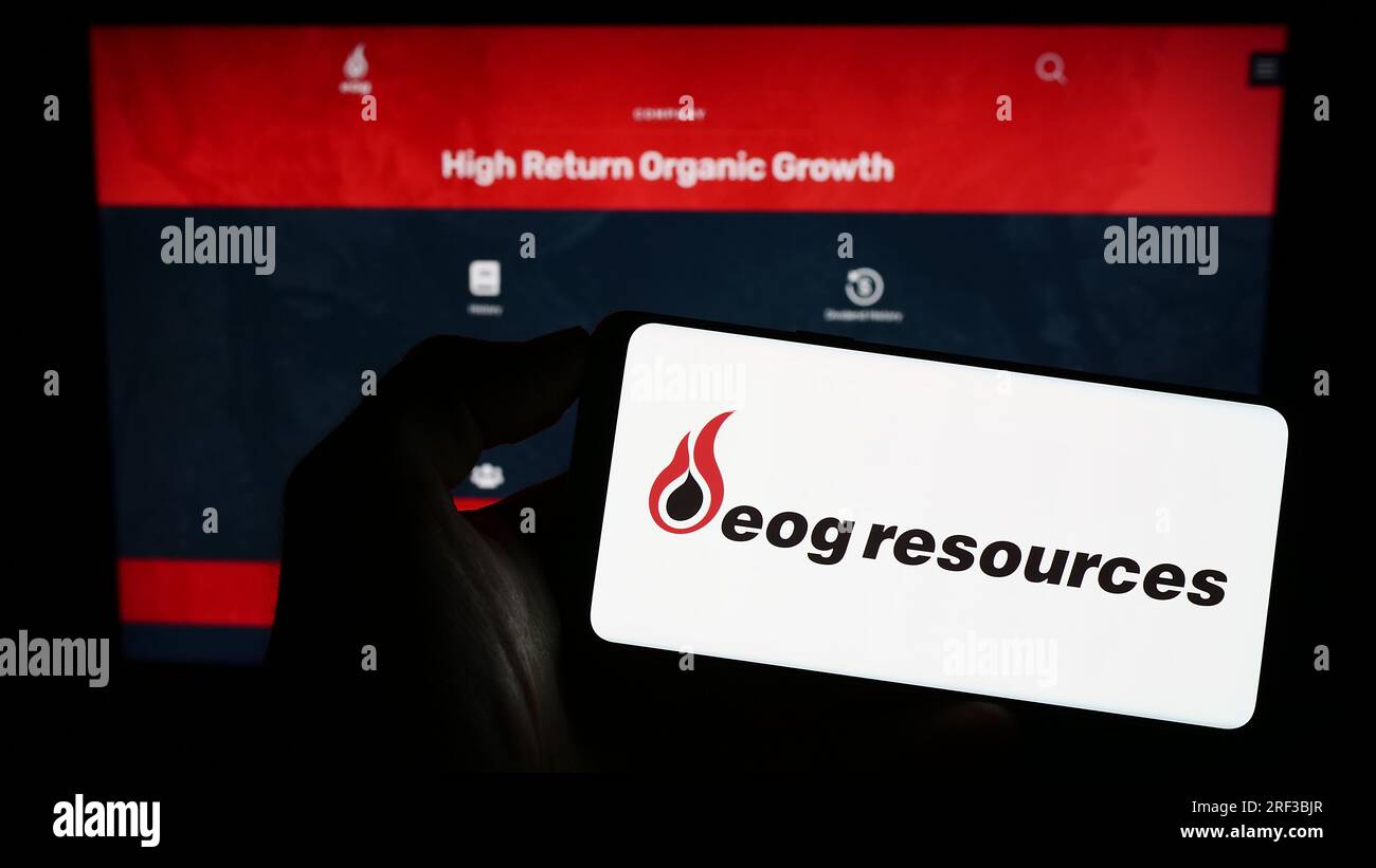 Person, die ein Mobiltelefon mit dem Logo des amerikanischen Energieunternehmens EOG Resources Inc. Auf dem Bildschirm vor der Webseite hält. Konzentrieren Sie sich auf das Display des Telefons. Stockfoto