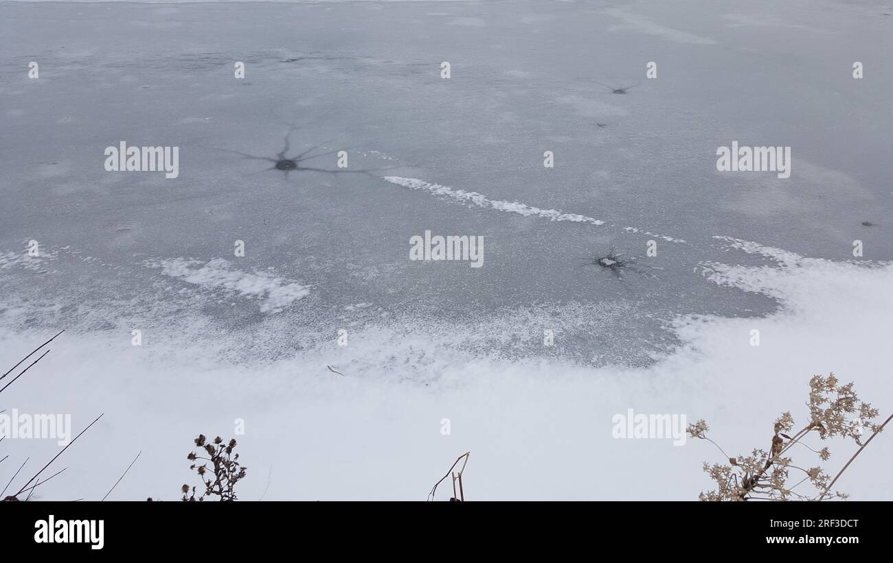 Gefrorener See mit mehreren Rissen und Löchern Stockfoto