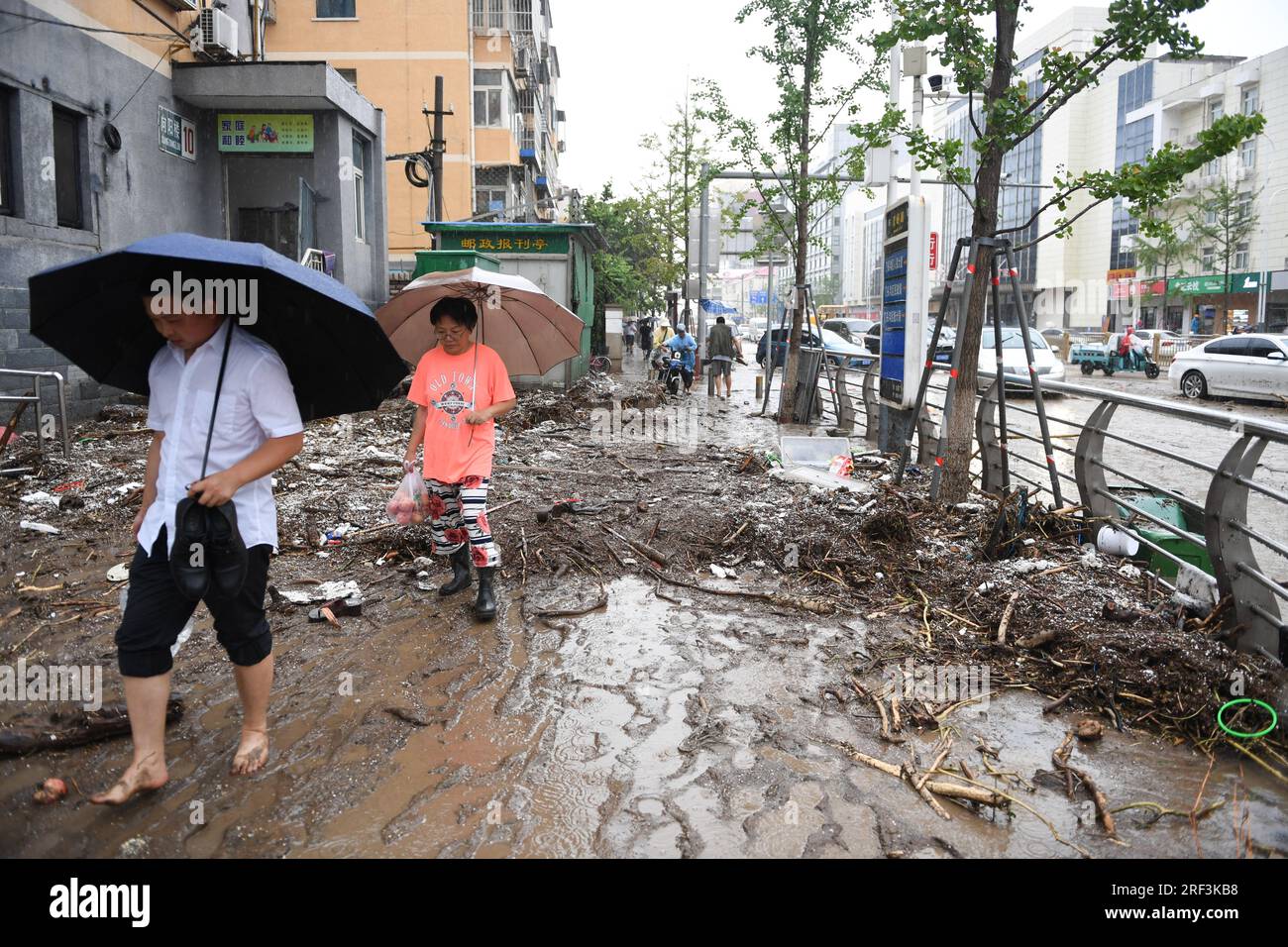 Peking, China. 31. Juli 2023. Passagiere gehen auf einer schlammigen Straße im vom Flut betroffenen Mentougou-Bezirk von Peking, Hauptstadt von China, 31. Juli 2023. Bis 4 Uhr Am Montag hatte die chinesische Hauptstadt 40 Stunden ununterbrochenen Regen erlebt. Die Daten zeigen, dass es ab 8 Uhr ist Samstag bis 3 Uhr Montag betrug die durchschnittliche Niederschlagsmenge in Peking 193,4 mm, wobei die maximale Niederschlagsmenge an einem malerischen Ort im Bezirk Mentougou 580 mm überstieg. Kredit: Ju Huanzong/Xinhua/Alamy Live News Stockfoto