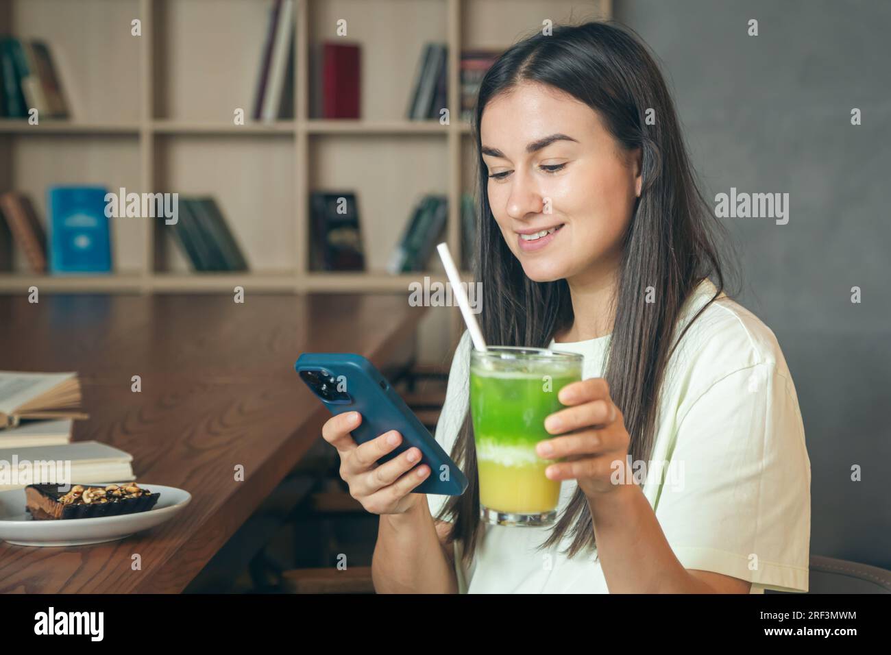 Eine Frau in einem Café mit einem Smartphone und einem Glas Limonade. Stockfoto