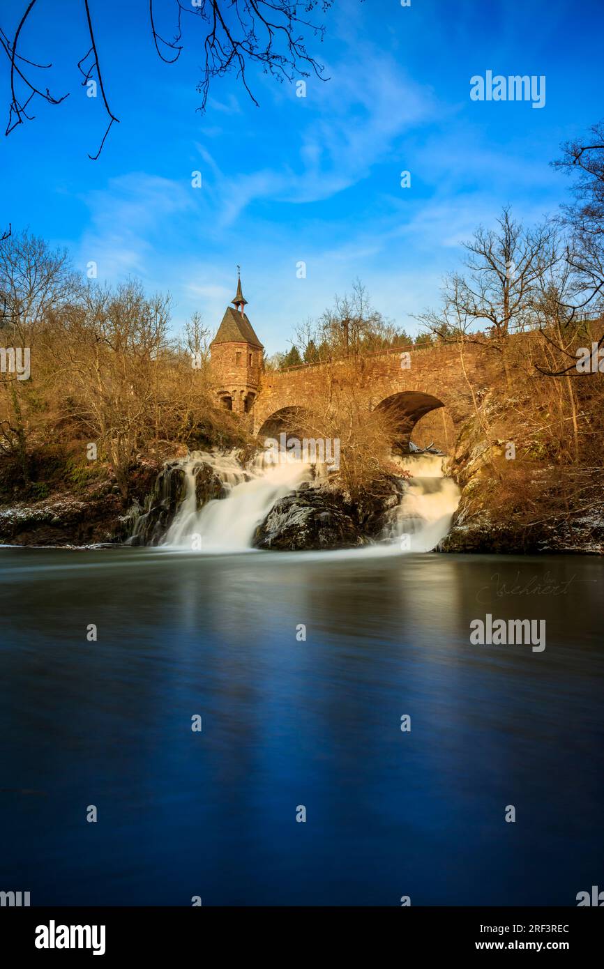 Pyrmont Mill in Rheinland-Pfalz Deutschland Steinbrücke mit Wasserfall, See und Fachwerkhaus. Eine Burgruine im Hintergrund Stockfoto