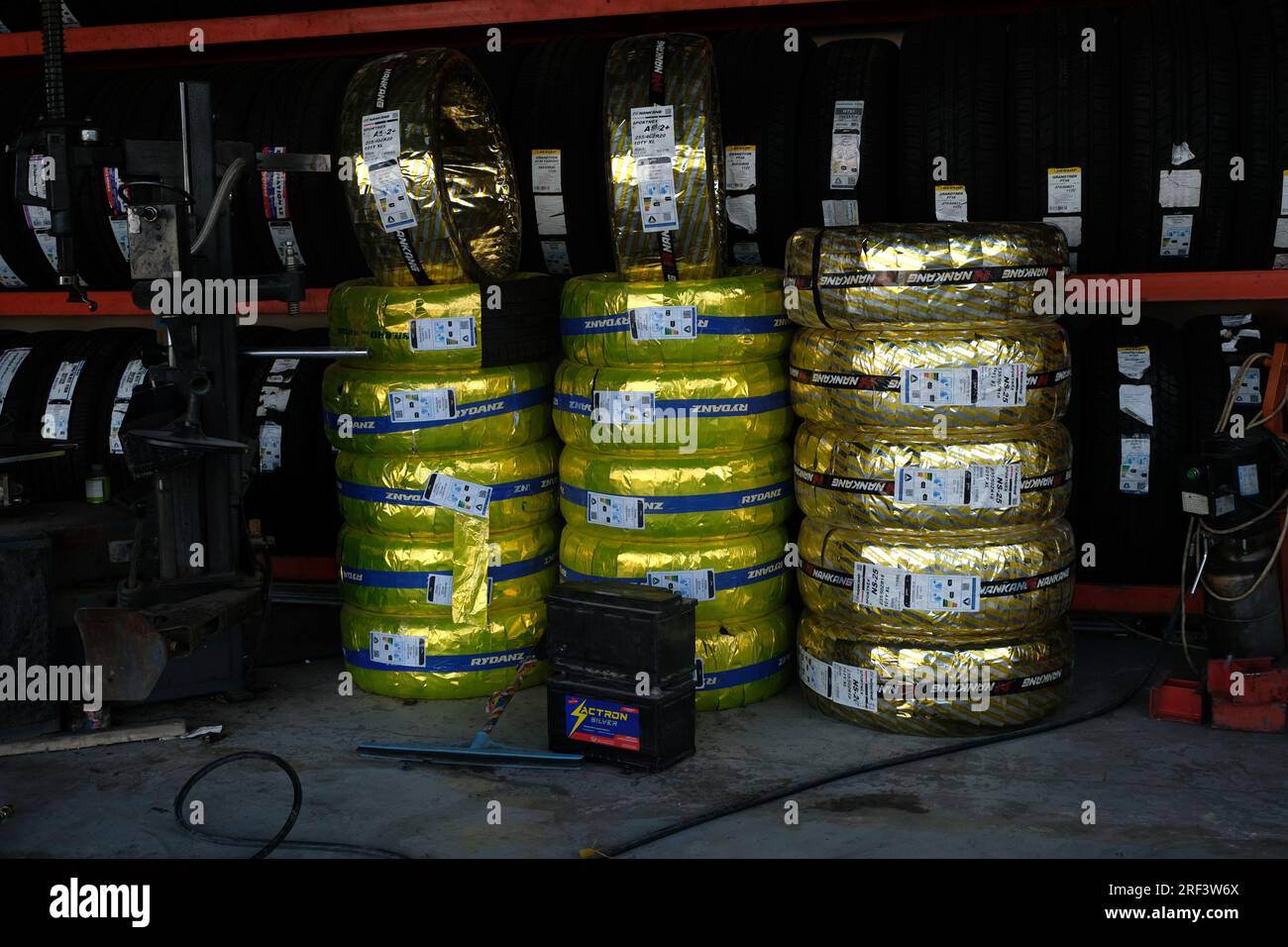 Lagerung neuer Reifen und Fahrzeugbatterie in einer Maschinenwerkstatt Stockfoto