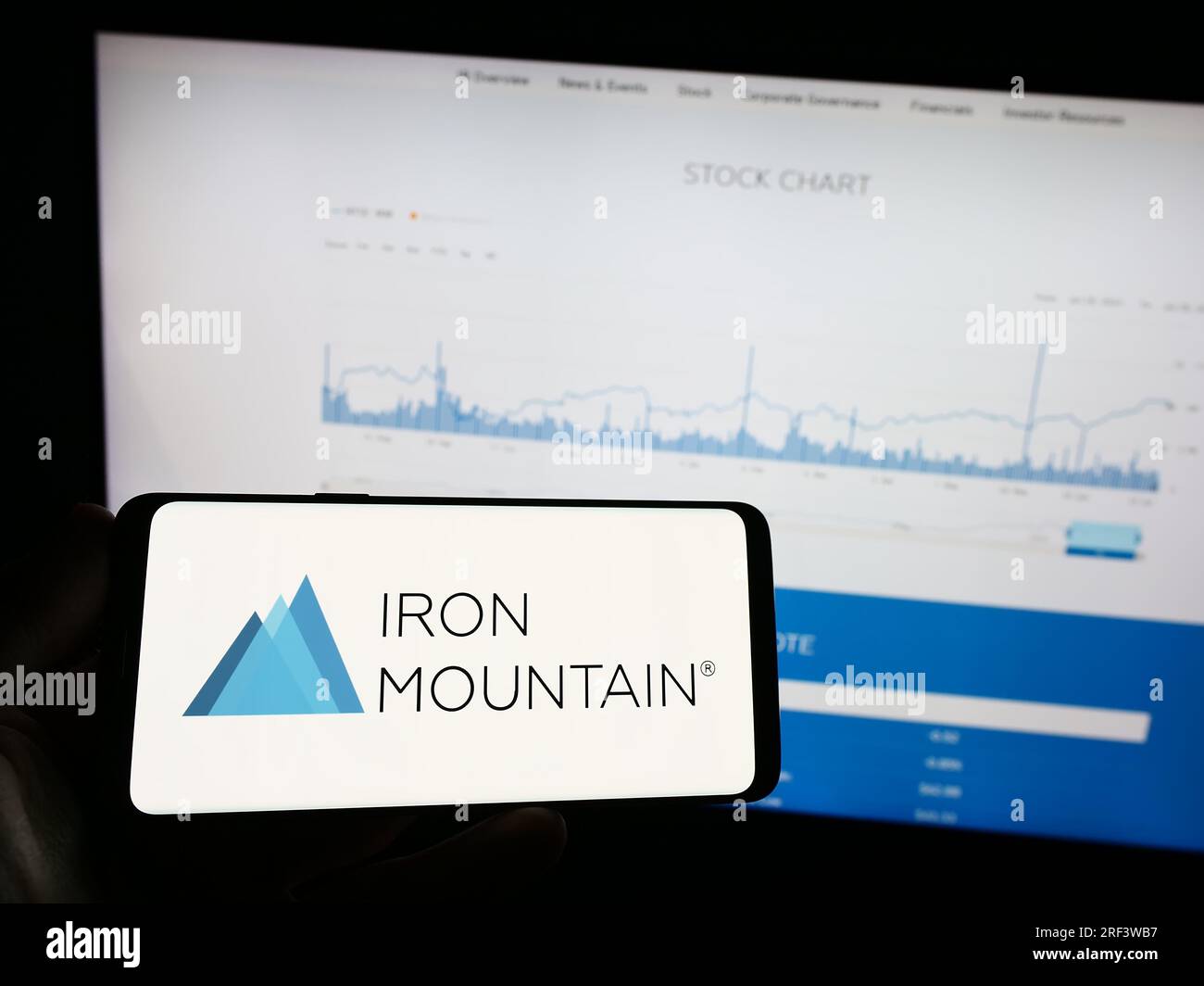 Person, die ein Mobiltelefon mit dem Logo des amerikanischen Unternehmens Iron Mountain Inc. Auf dem Bildschirm vor der Unternehmenswebseite hält. Konzentrieren Sie sich auf das Display des Telefons. Stockfoto