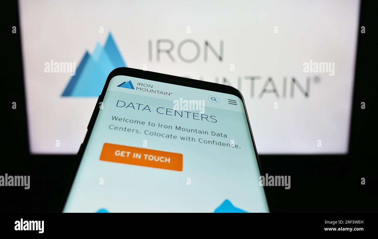Mobiltelefon mit Website des US-Unternehmens Iron Mountain Inc. Auf dem Bildschirm vor dem Unternehmenslogo. Fokus auf oberer linker Seite des Telefondisplays. Stockfoto