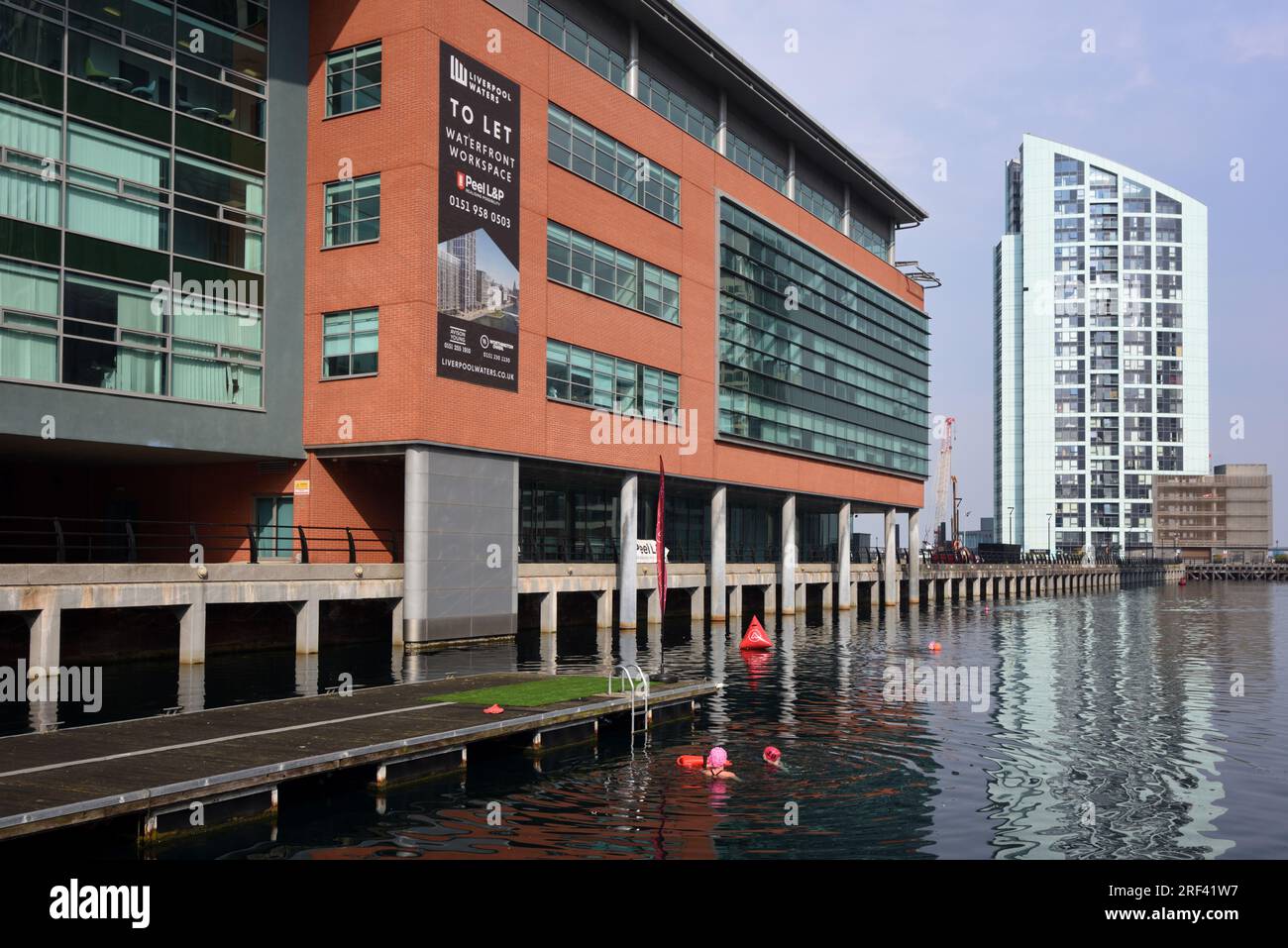Schwimmer schwimmen im Prince's Dock mit Alexandra Tower (2005-2008) im Background Liverpool UK Stockfoto